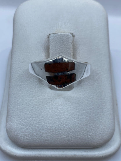 Anillo de plata con piedra cafe en forma de escudo sobre caja blanca