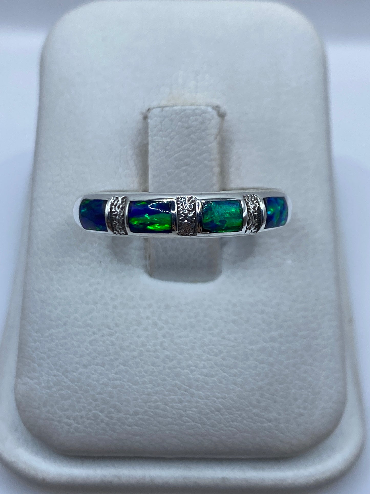 Anillo de plata .950 con ópalo de fuego azul engastado, visto de frente en la mano