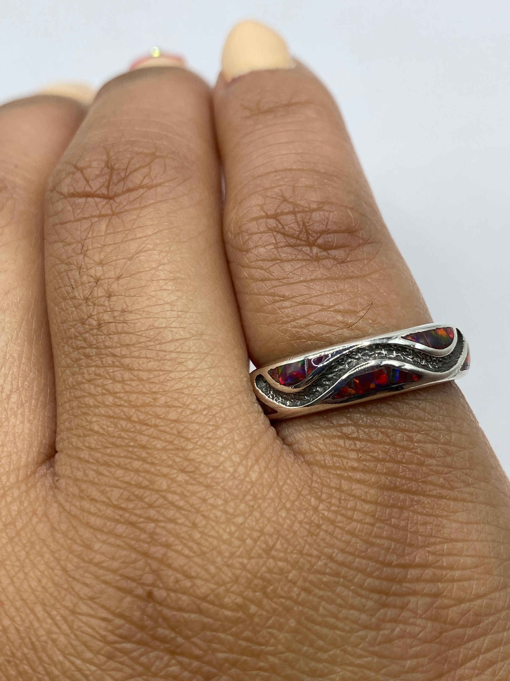 Anillo en mano mostrando los colores cambiantes del ópalo bajo luz natural