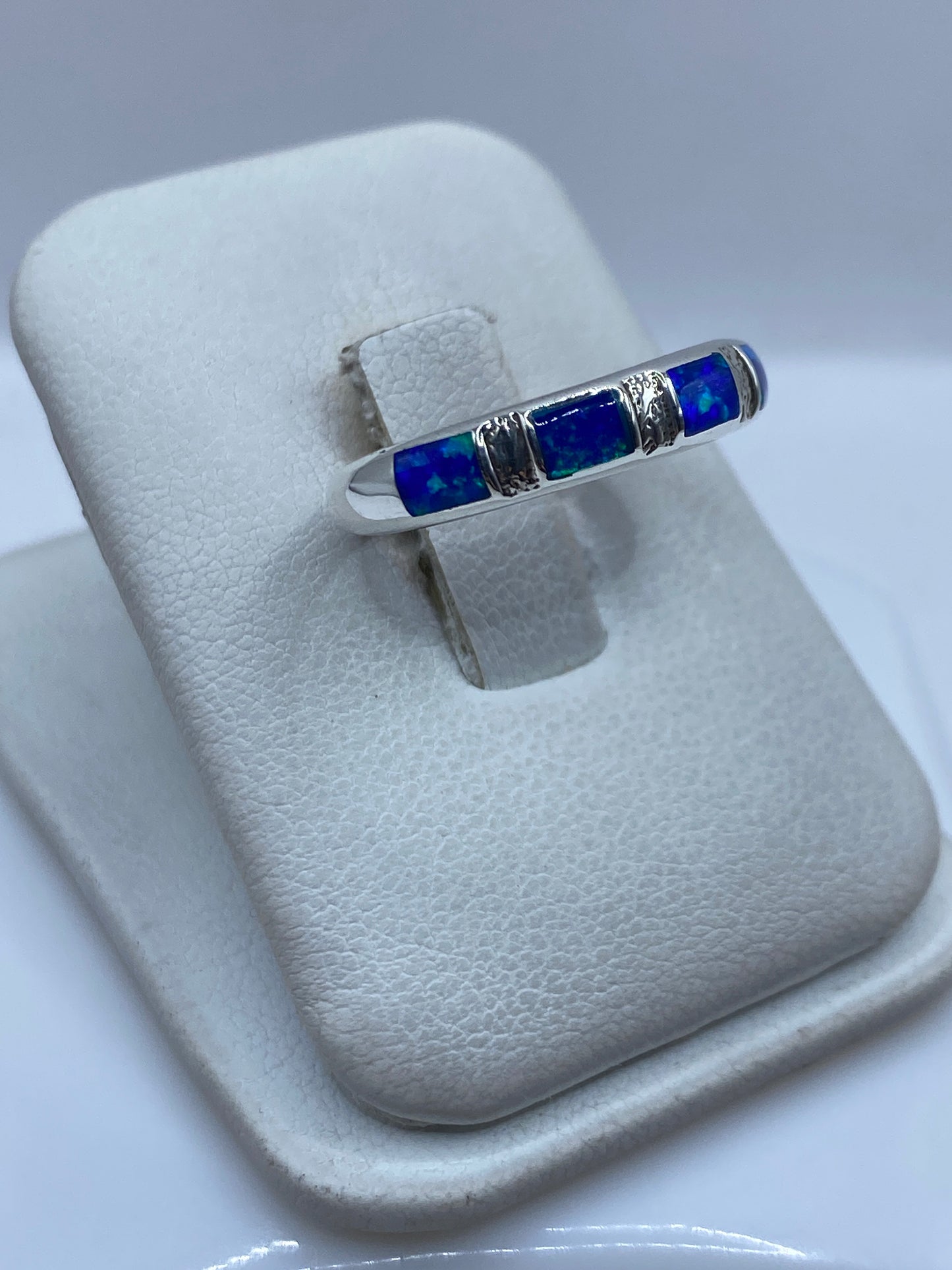 Detalle del ópalo de fuego azul engastado entre bandas de plata pura en la mano