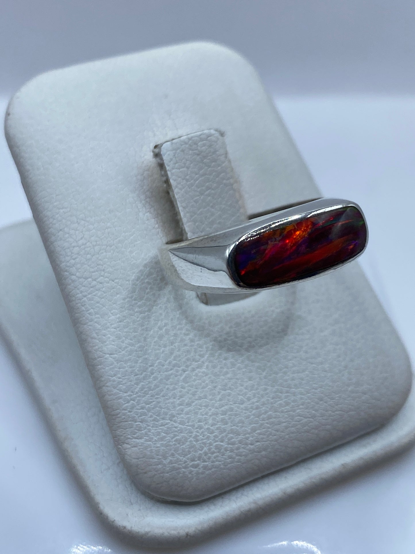 Vista lateral del anillo mostrando el ópalo multicolor engastado en plata pulida