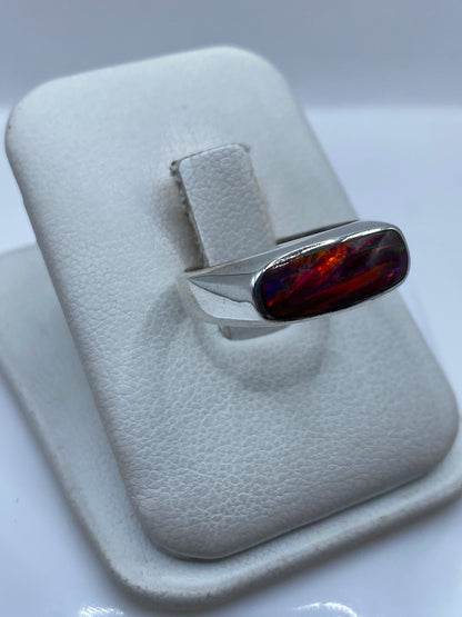 Vista lateral del anillo mostrando el ópalo multicolor engastado en plata pulida