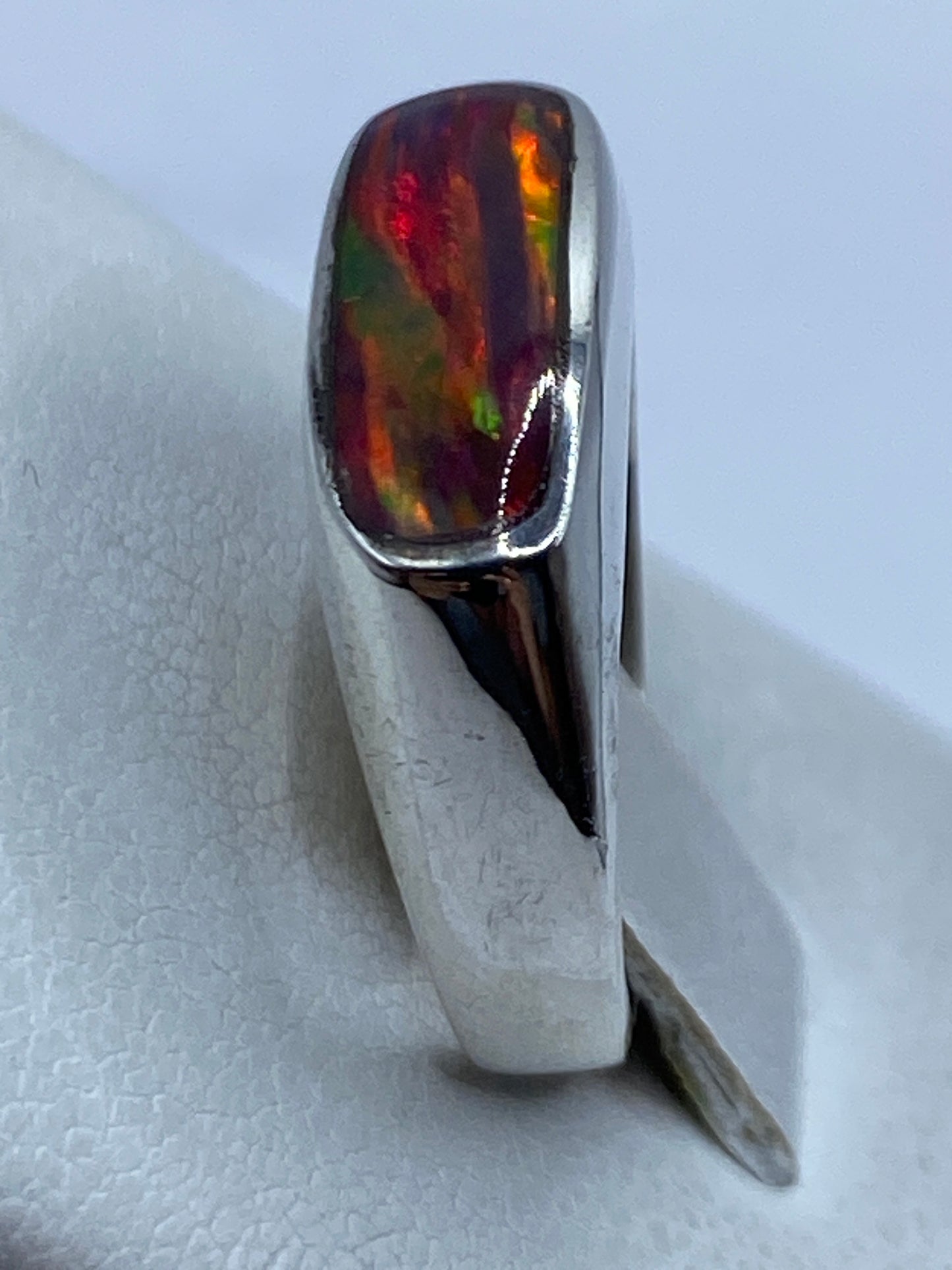 Detalle de la piedra de ópalo reflejando luz en múltiples colores dentro del engaste