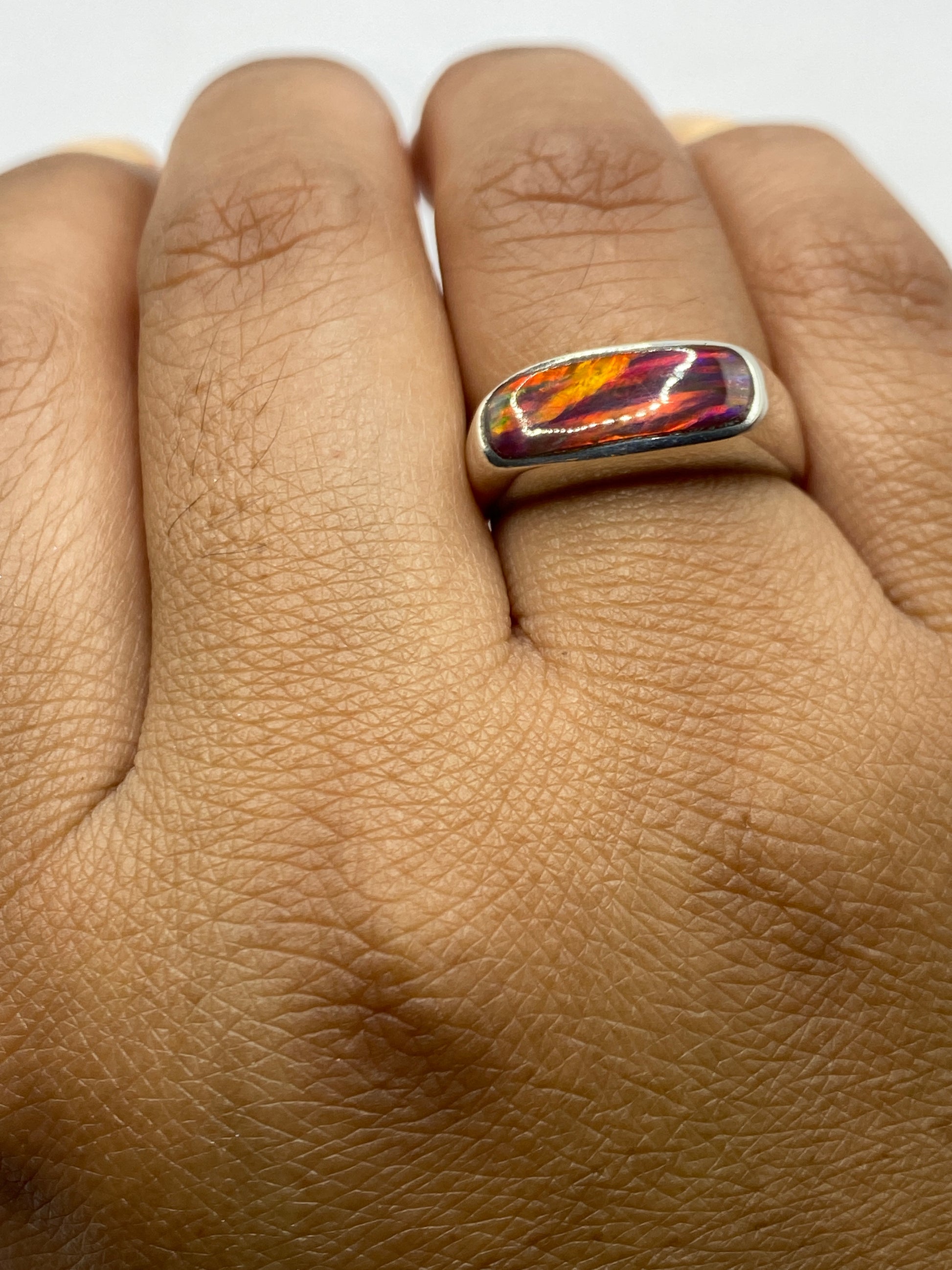 Anillo en la mano mostrando el tamaño y el juego de colores del ópalo de fuego