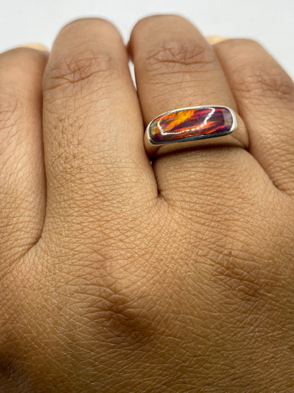 Anillo en la mano mostrando el tamaño y el juego de colores del ópalo de fuego