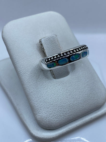 Vista frontal del anillo mostrando el ópalo de fuego con reflejos azules y verdes