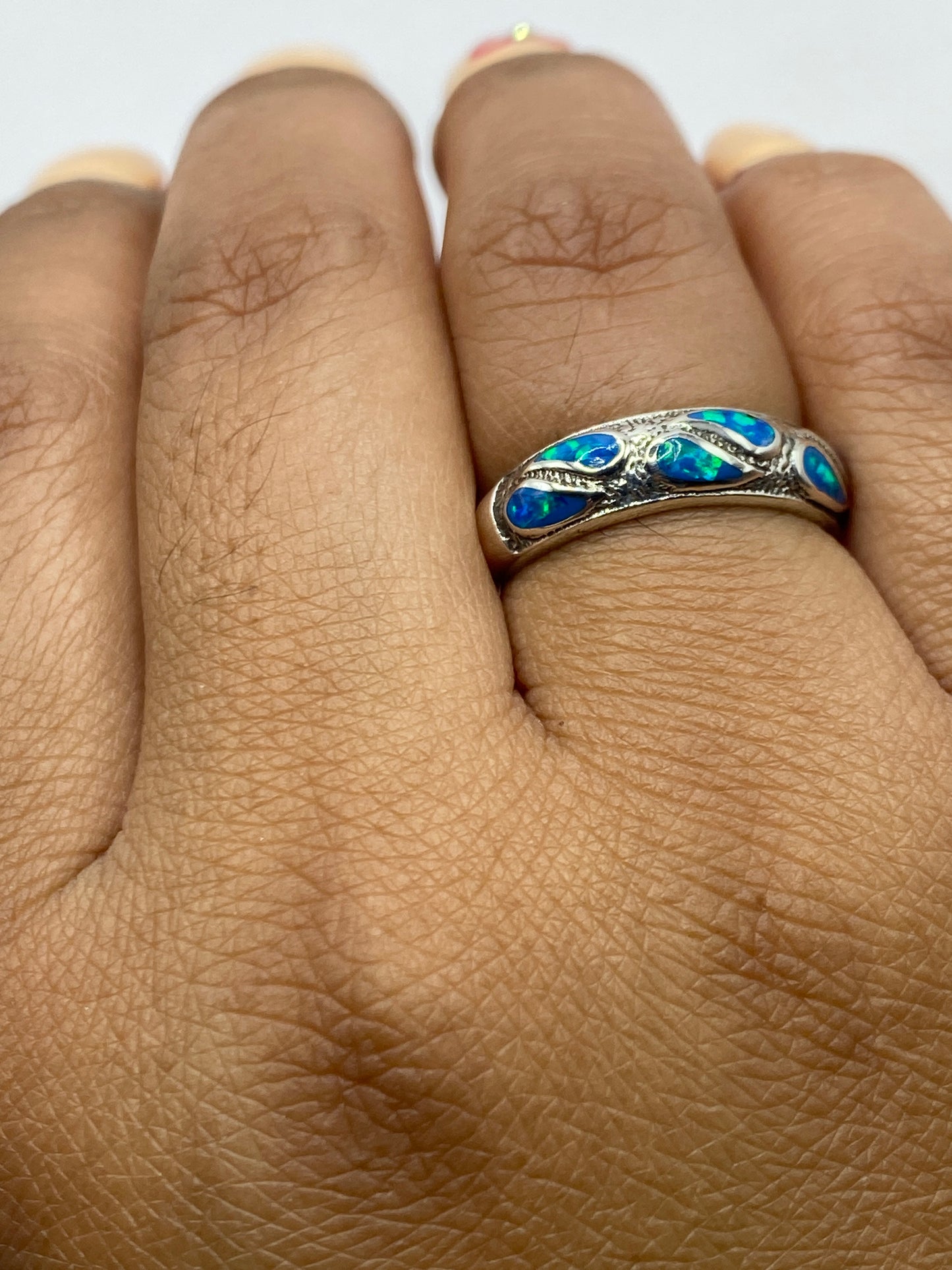 Anillo puesto en dedo mostrando el brillo del ópalo de fuego azul
