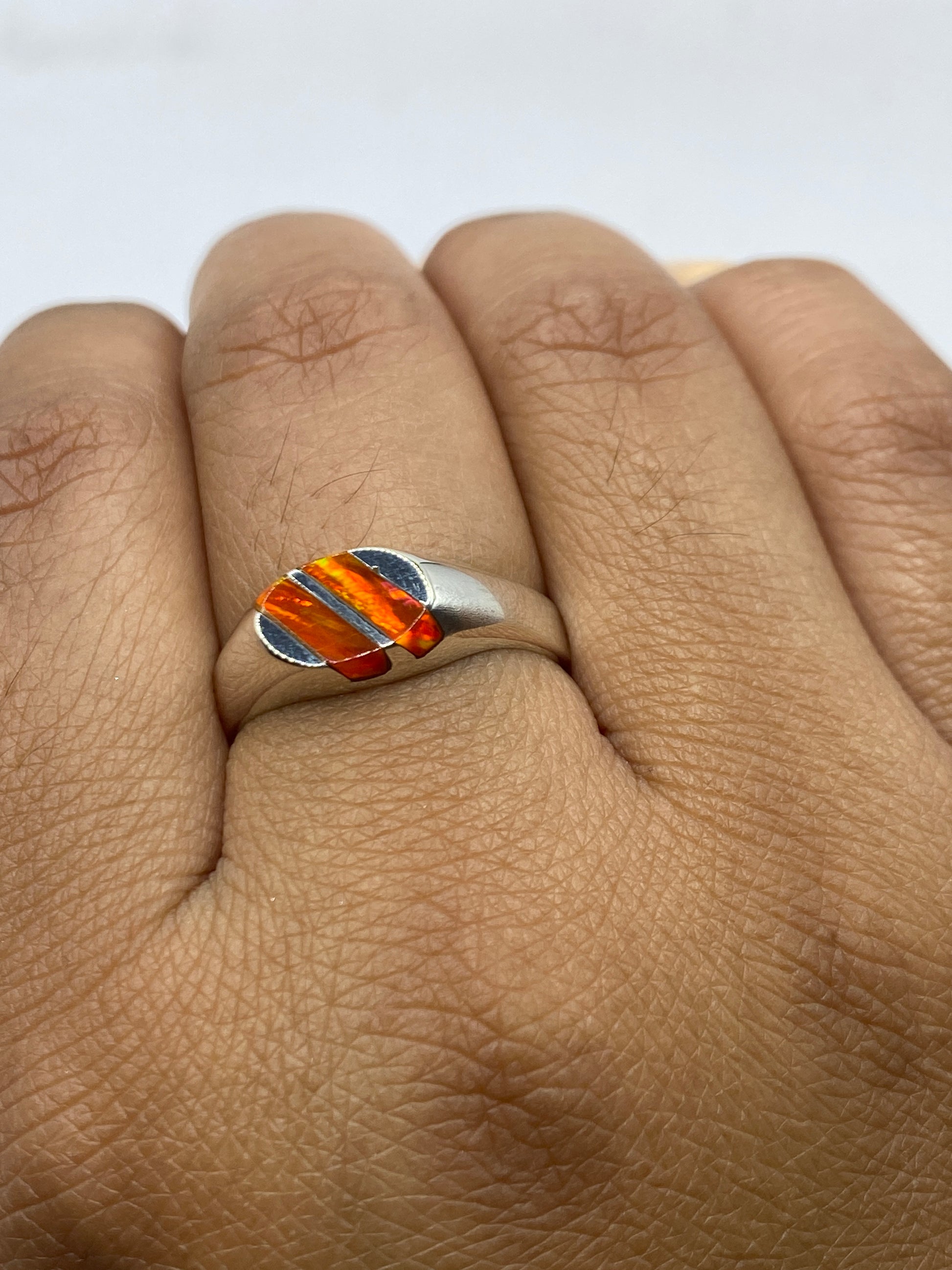 Anillo en la mano luciendo el ópalo de fuego con luz natural, talla 8