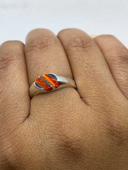 Anillo en la mano luciendo el ópalo de fuego con luz natural, talla 8
