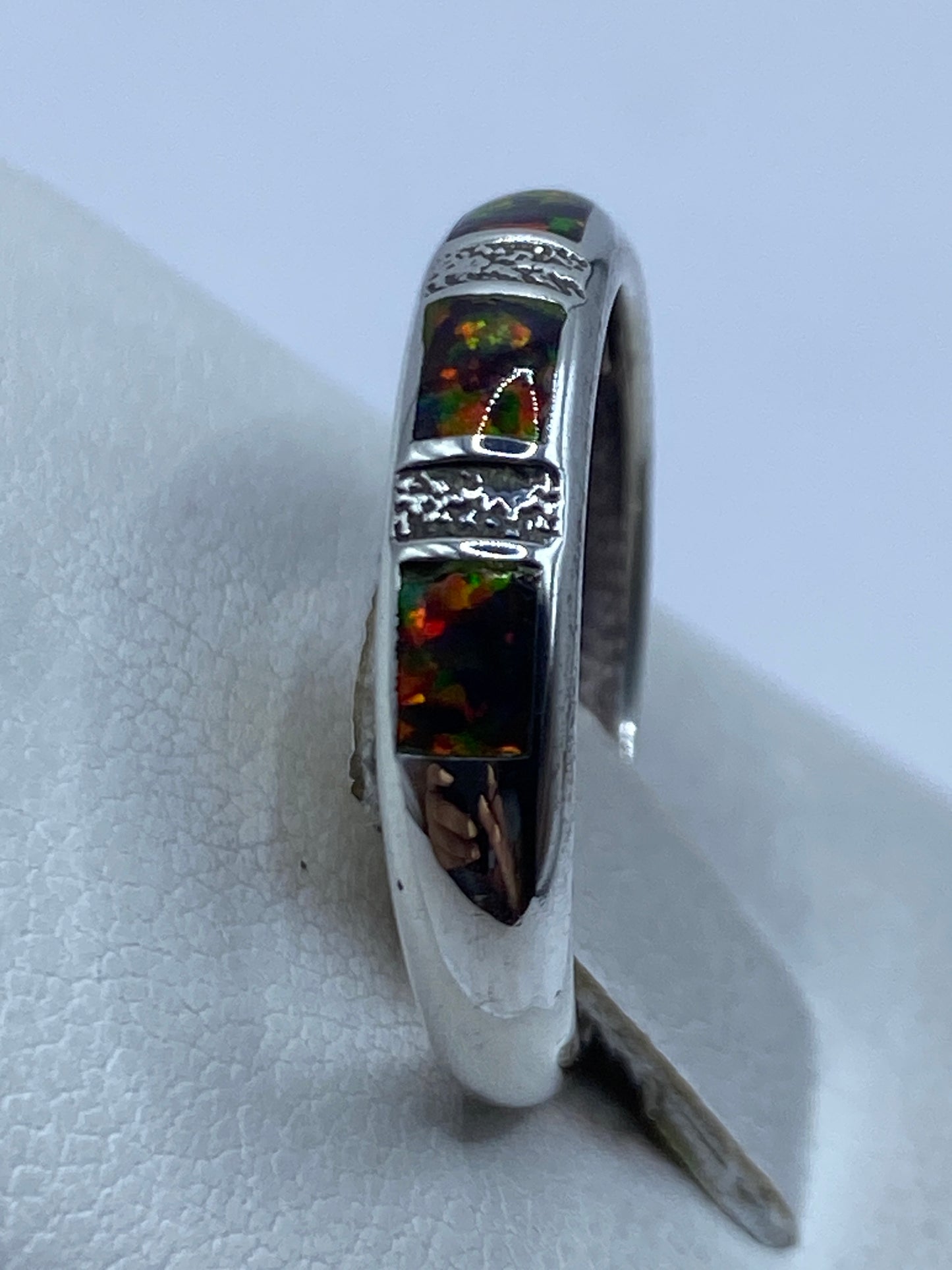 Anillo de ópalo en la mano mostrando los tonos multicolor bajo la luz