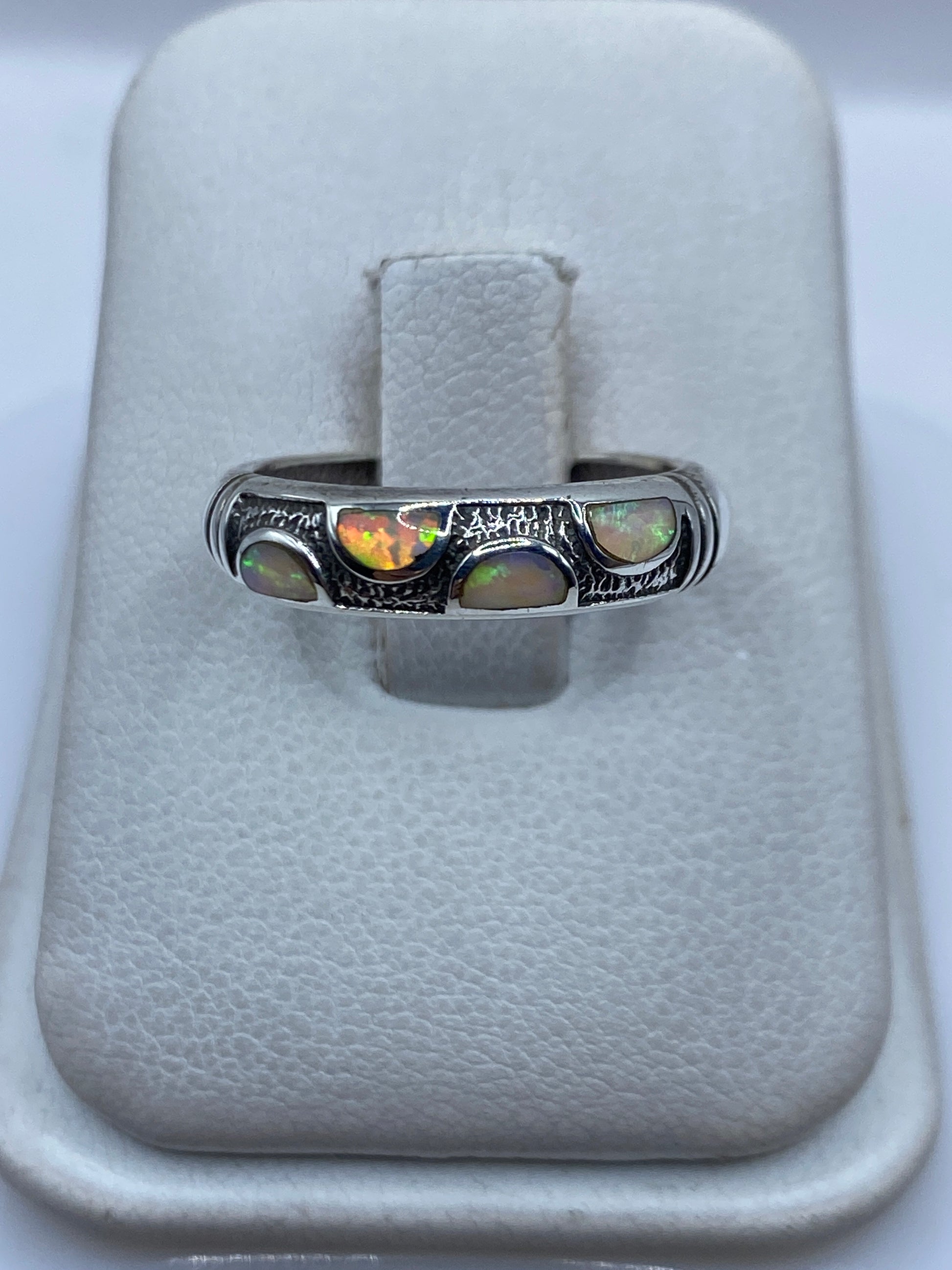 Anillo de plata con Opalo de Fuego multicolor engastado a mano, vista frontal en joyero blanco