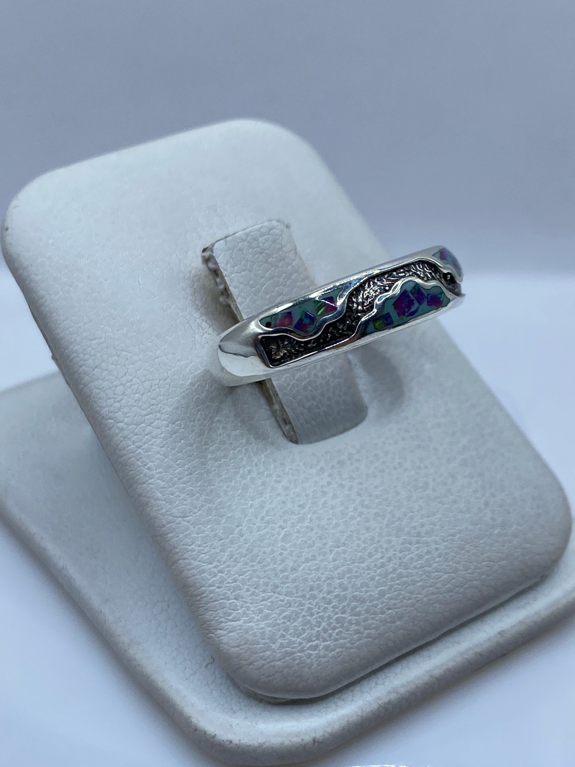 Vista lateral del anillo mostrando el engaste de la piedra ópalo y el pulido de la plata