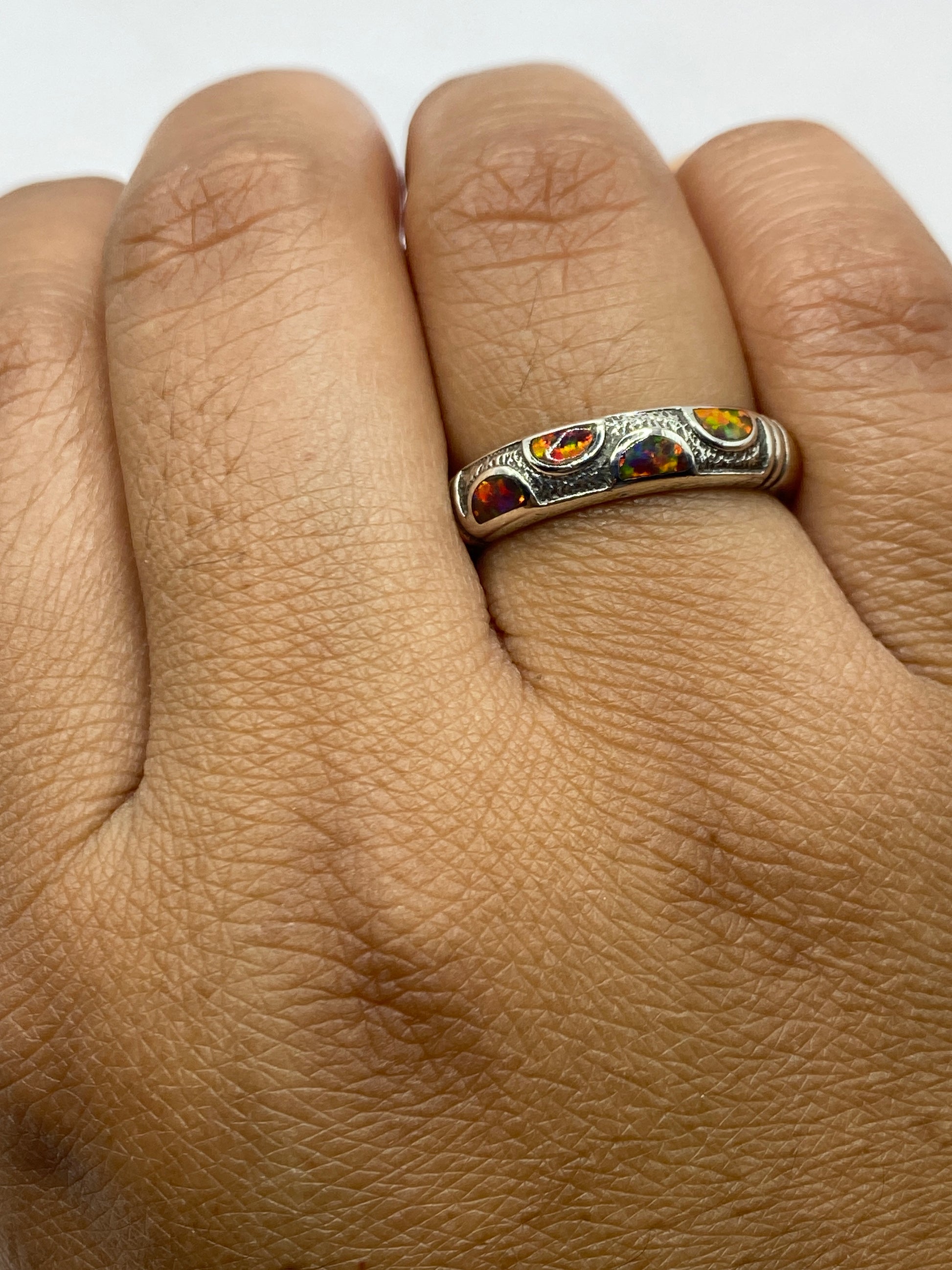 Anillo de plata en dedo mostrando el brillo multicolor del ópalo de fuego