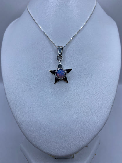Detalle frontal del dije estrella mostrando el engaste de la piedra multicolor