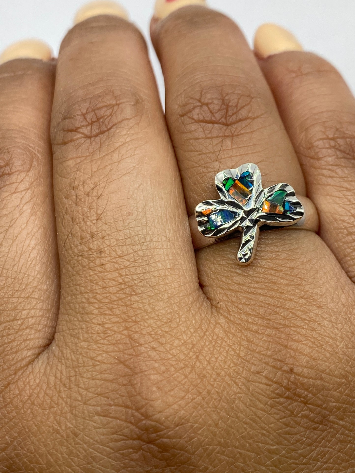 Anillo en dedo mostrando la iridiscencia del ópalo de fuego bajo luz natural