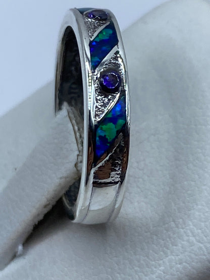 Anillo personalizado de plata .950 en dedo, mostrando los destellos azules del ópalo