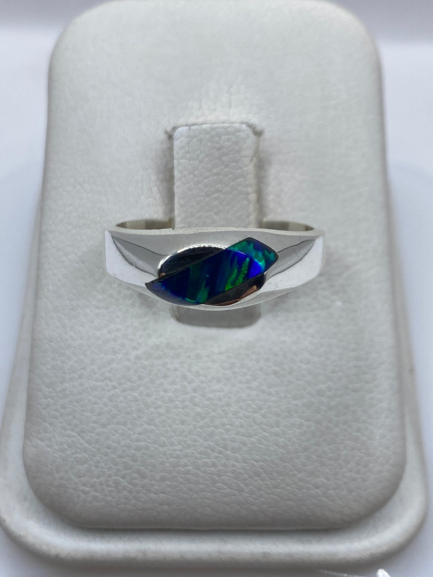 Anillo de plata .950 con ópalo de fuego azul intenso en mano, mostrando el juego de colores