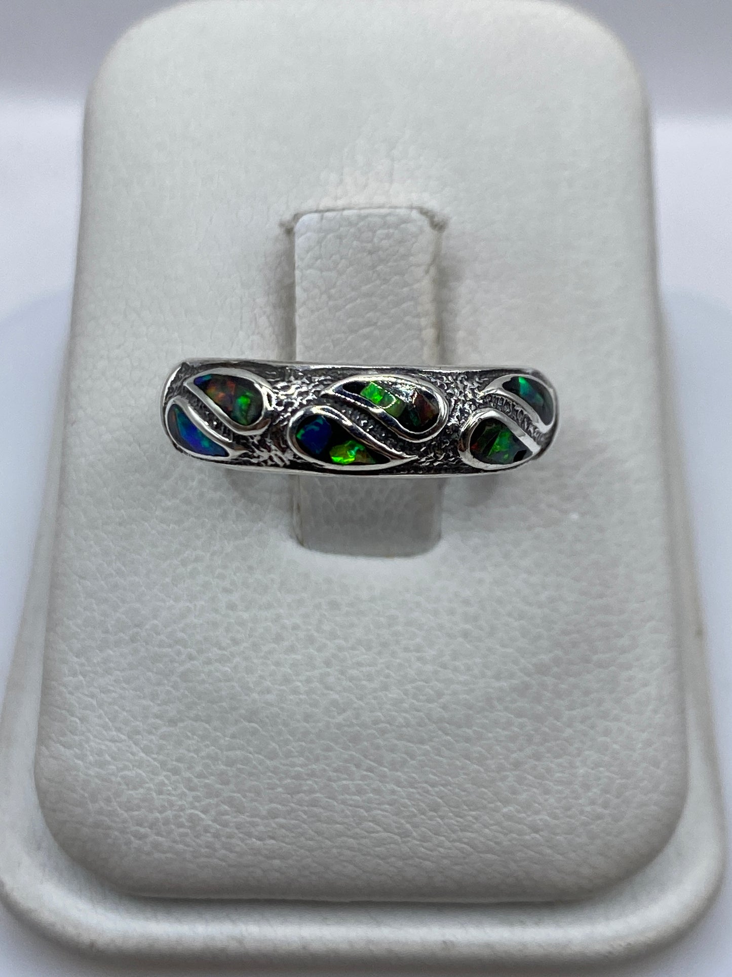 Anillo de plata con ópalo de fuego multicolor, destellos azules y verdes sobre fondo blanco