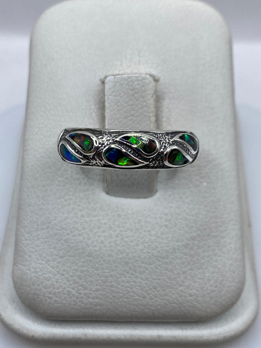Anillo de plata con ópalo de fuego multicolor, destellos azules y verdes sobre fondo blanco