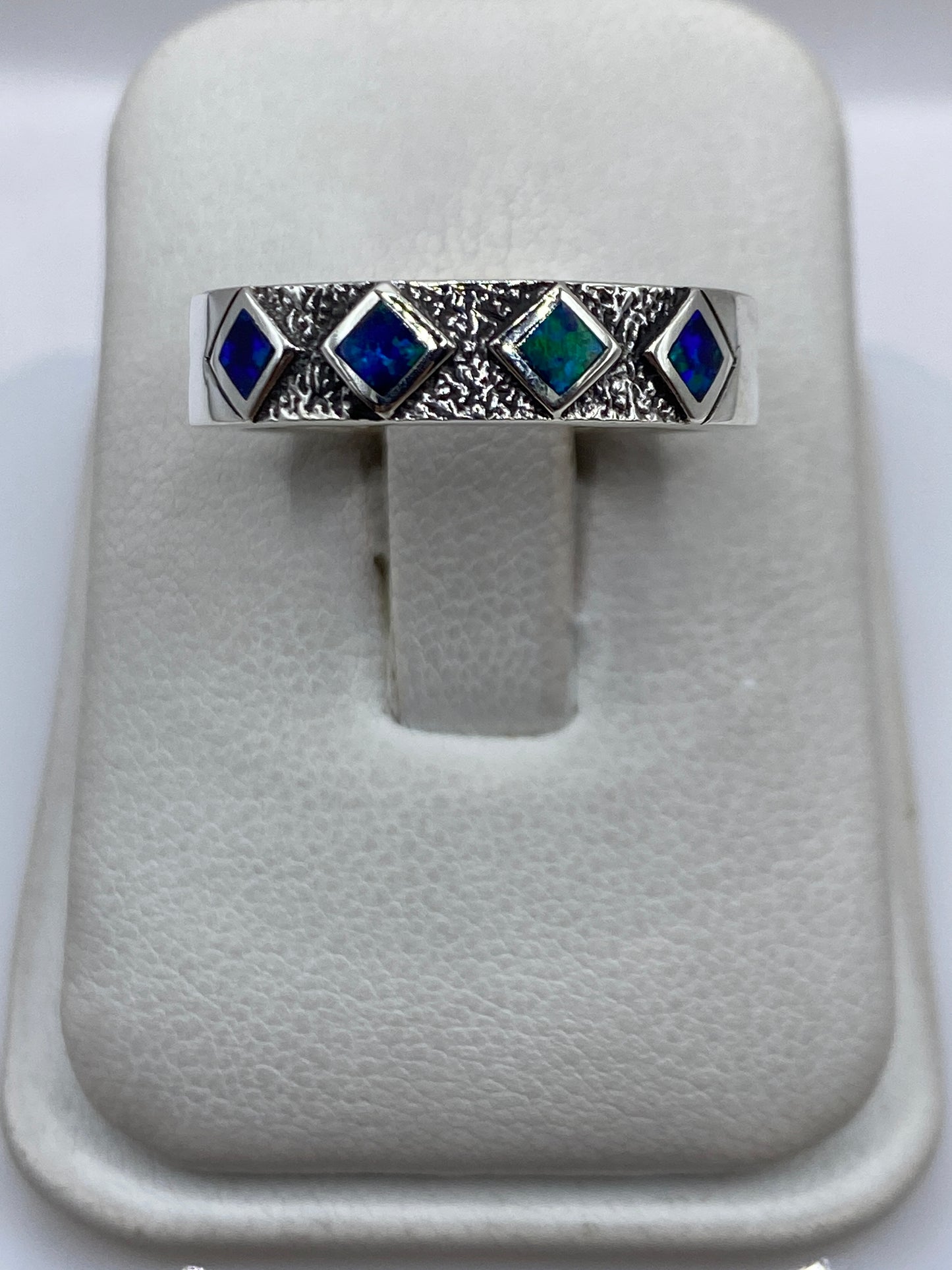 Anillo de plata .950 con ópalo de fuego azul en textura granulada, visto de frente en presentador