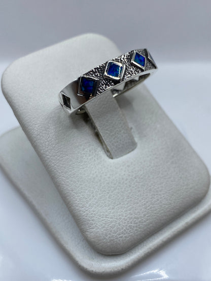 Detalle lateral del anillo mostrando el engaste a mano del ópalo azul profundo