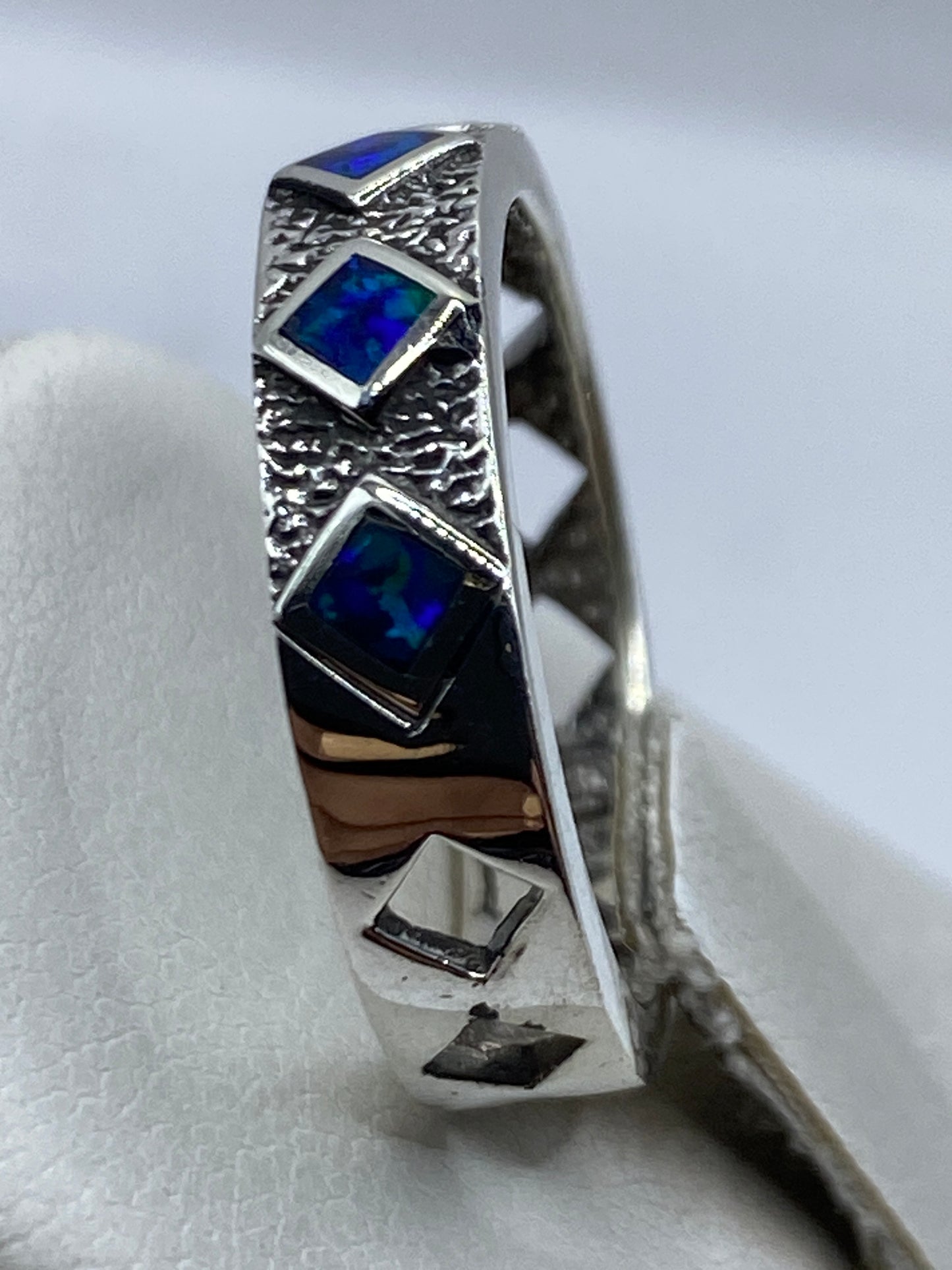 Anillo en la mano mostrando el juego de luz azul y turquesa del ópalo de fuego