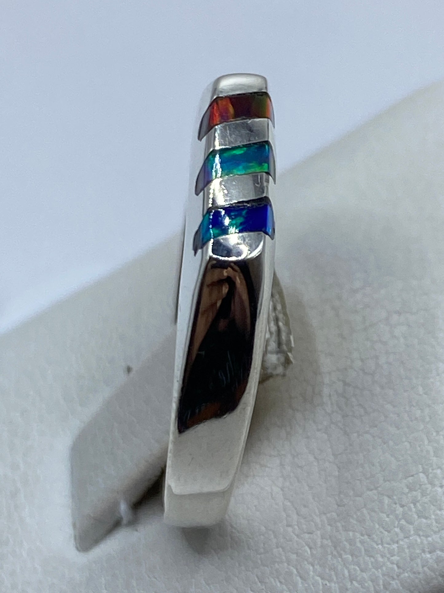 Ópalo de fuego multicolor brillando en talla 9, vista en mano