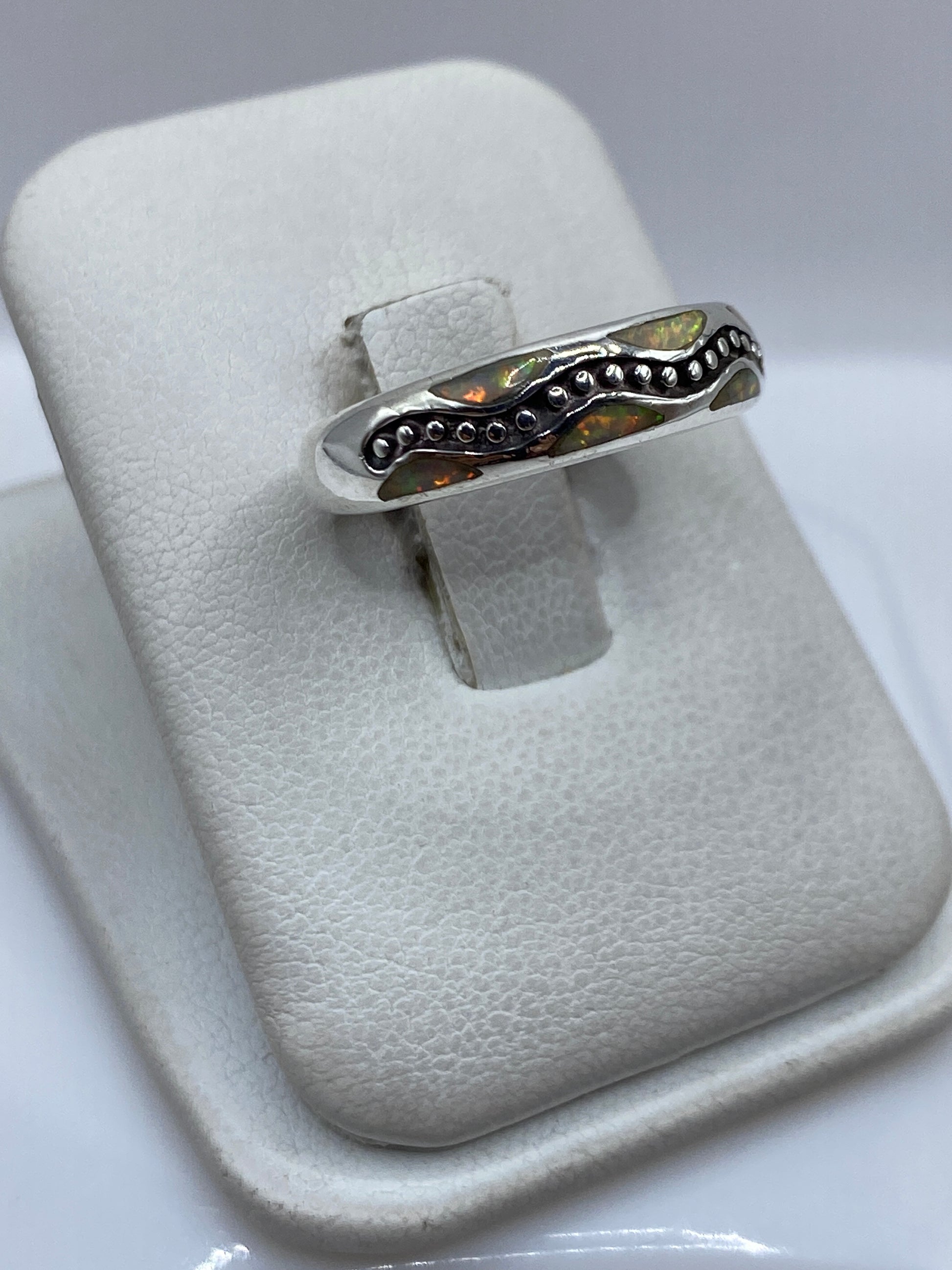 Detalle frontal del anillo mostrando el ópalo de fuego amarillo incrustado a mano con destellos de luz