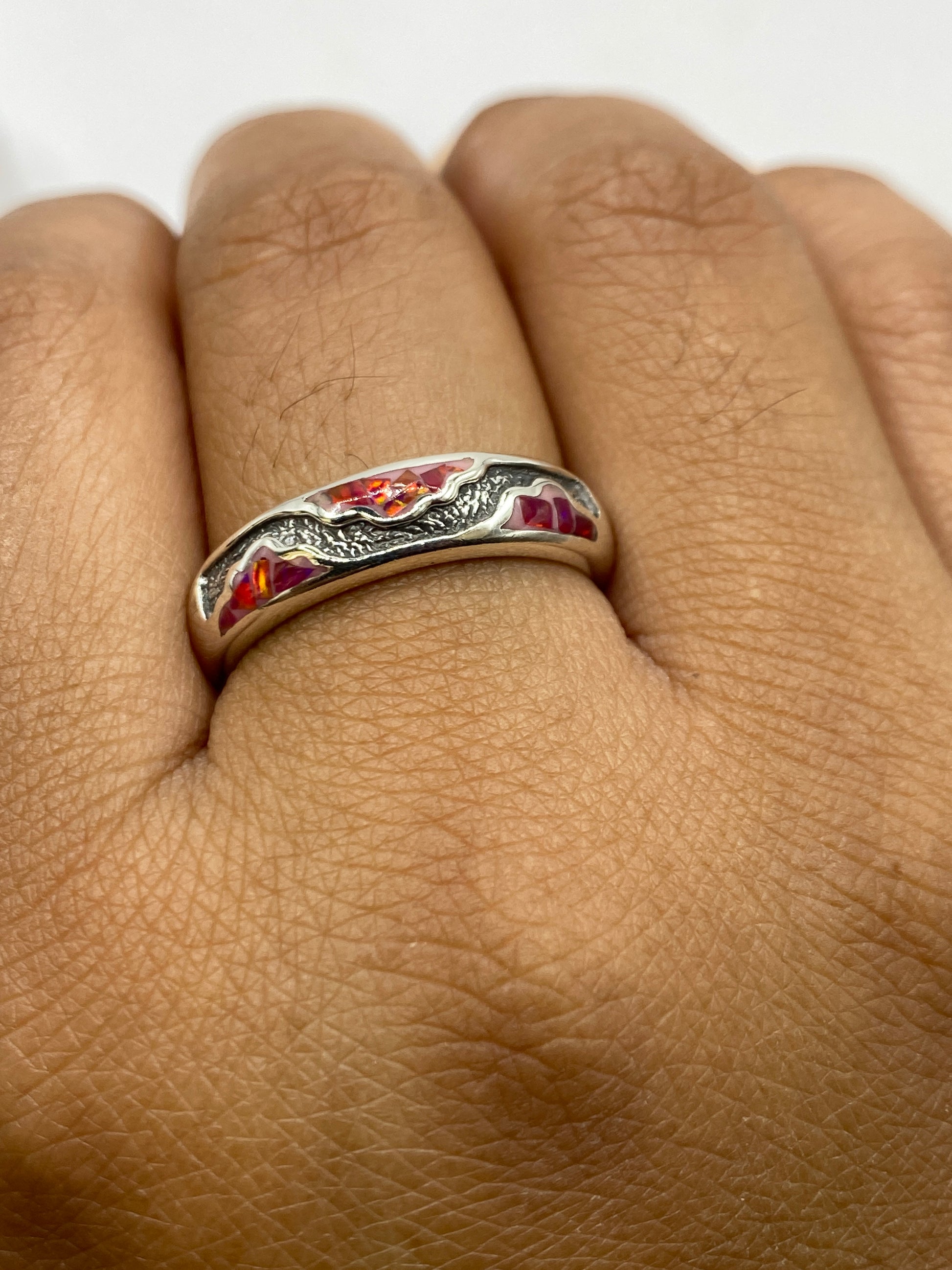 Anillo en mano mostrando la belleza del ópalo en color rosa coral