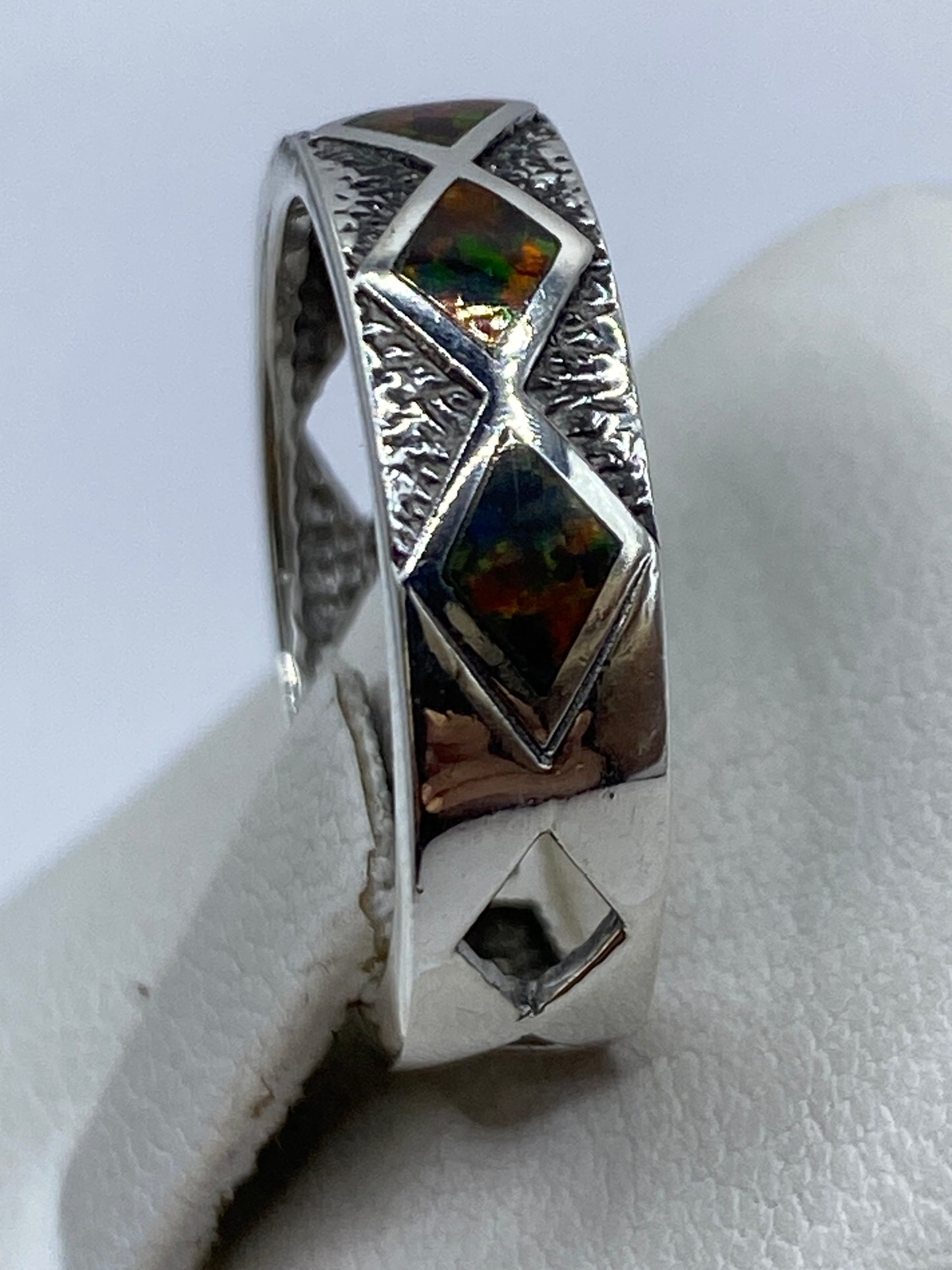 Anillo puesto en dedo índice, ópalo brillando con luz natural