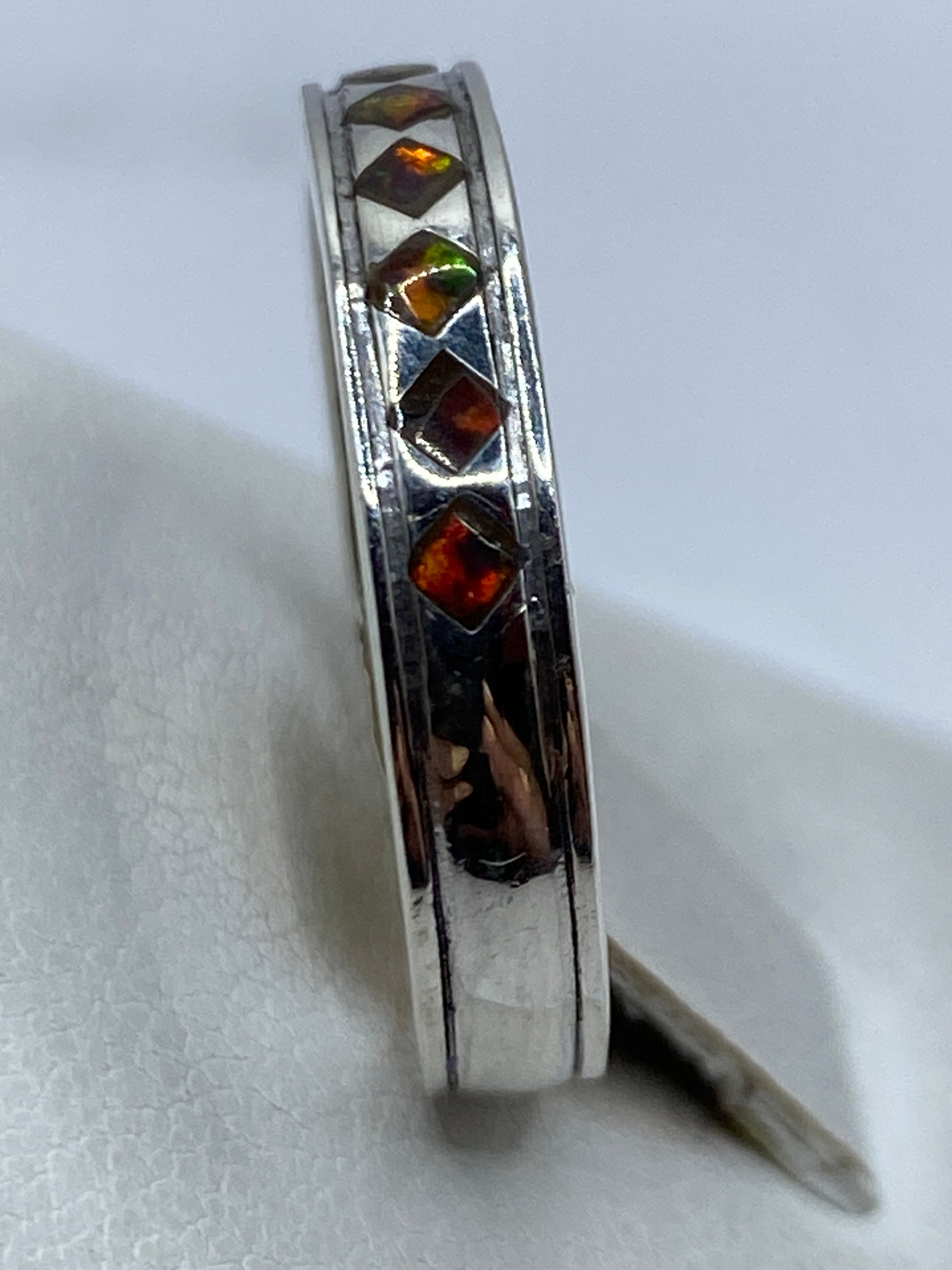Anillo con ópalo de fuego puesto en dedo, mostrando el juego de luces multicolor