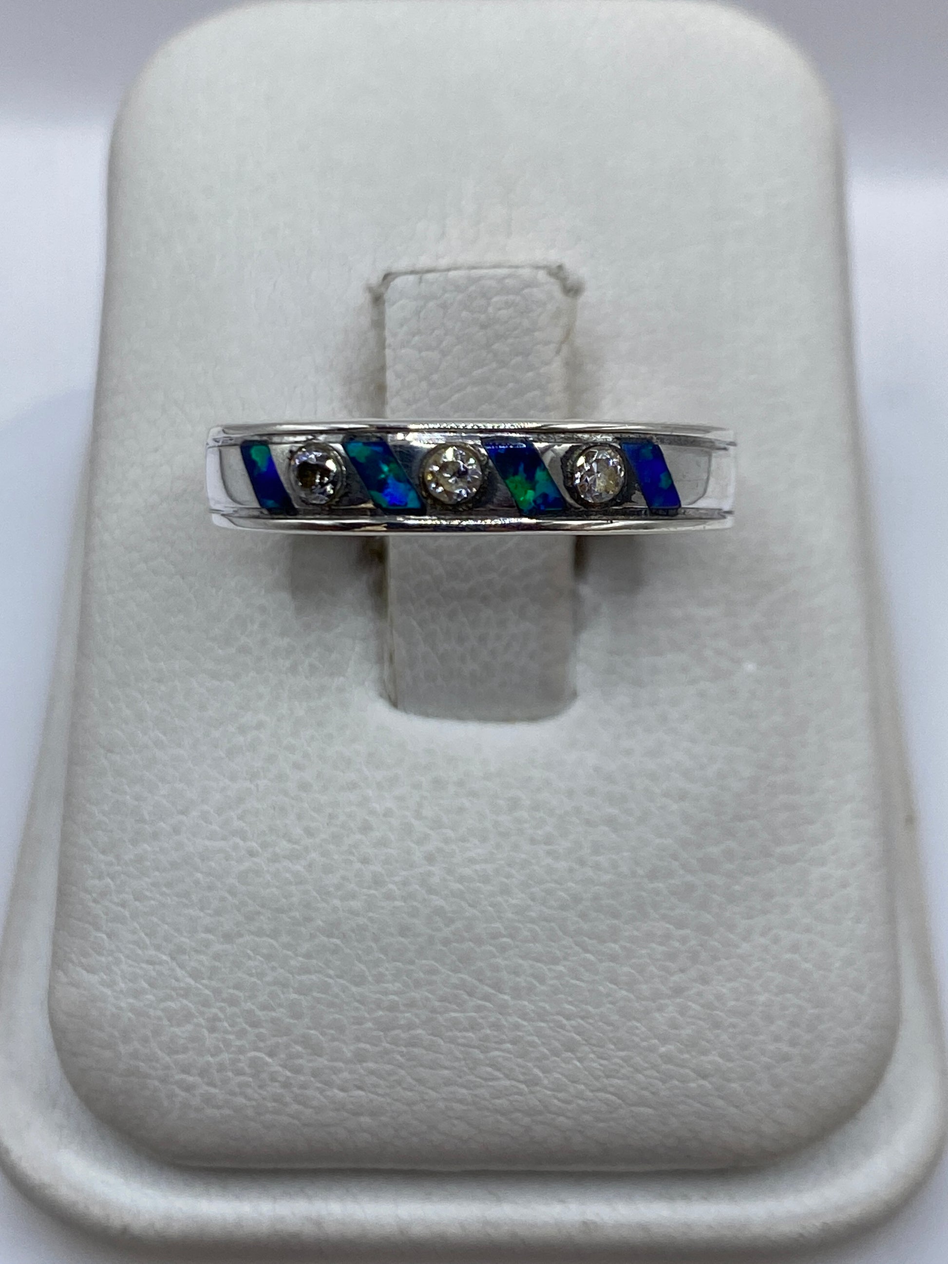 Anillo de plata .950 con ópalo de fuego azul incrustado en banda ancha, sobre blanco