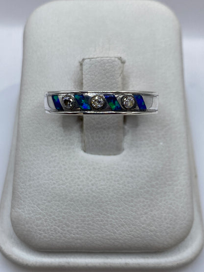 Anillo de plata .950 con ópalo de fuego azul incrustado en banda ancha, sobre blanco