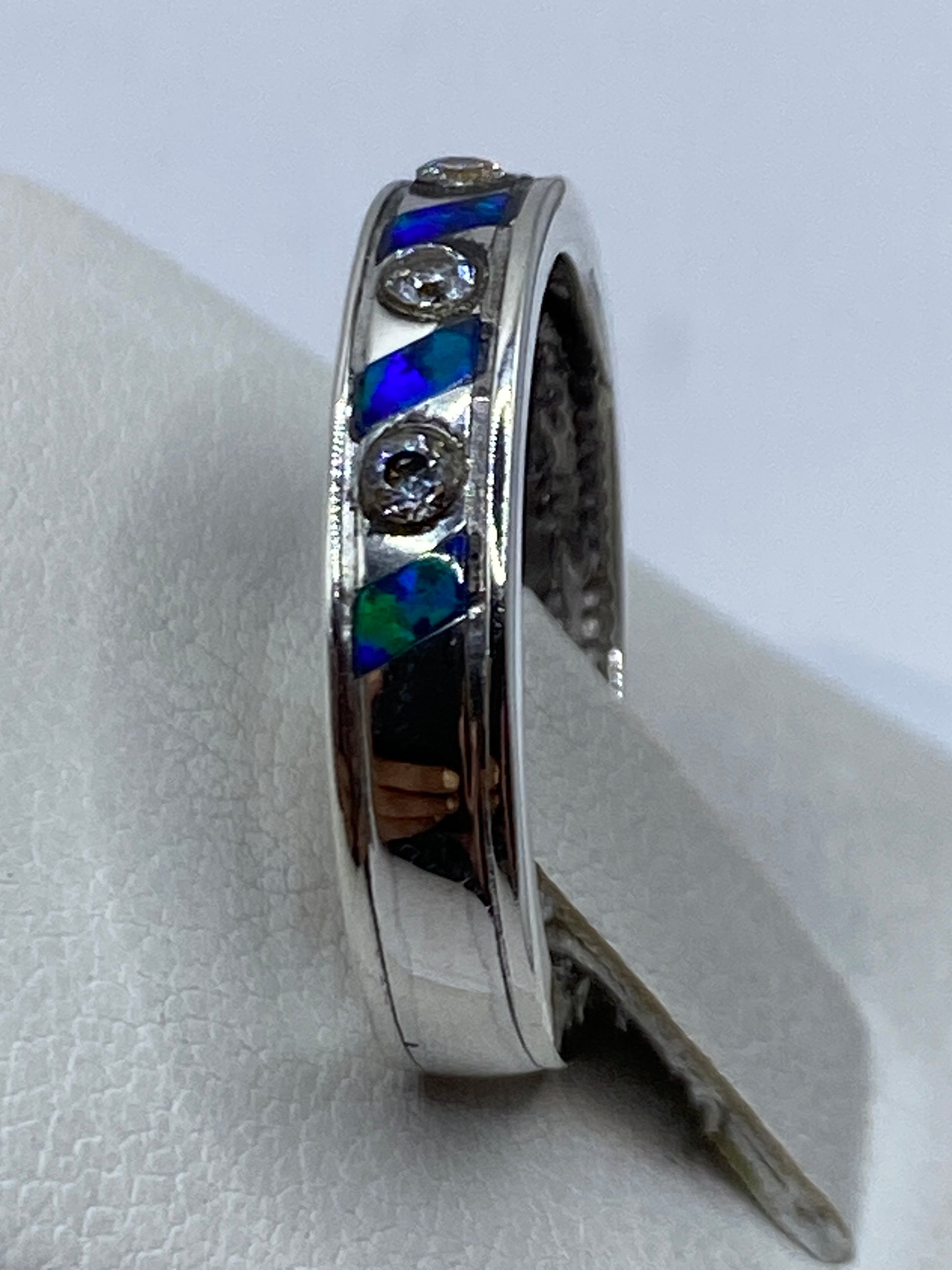 Detalle lateral del anillo en mano, resaltando la profundidad del color azul del ópalo