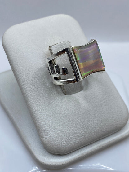 Vista lateral del anillo mostrando diseño calado en plata y engaste de ópalo