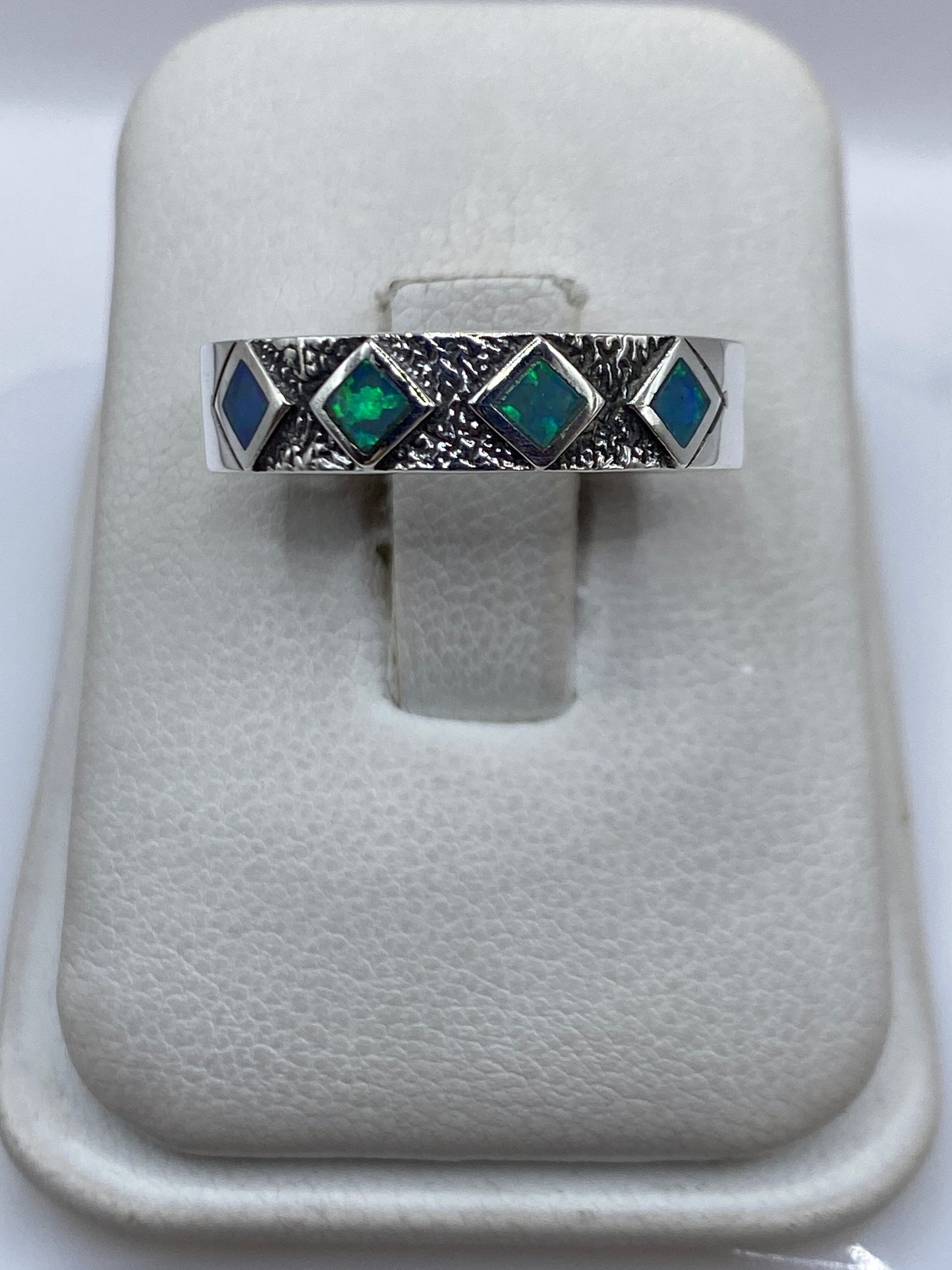 Anillo de plata .950 con ópalo de fuego azul cielo, vista frontal sobre presentador blanco