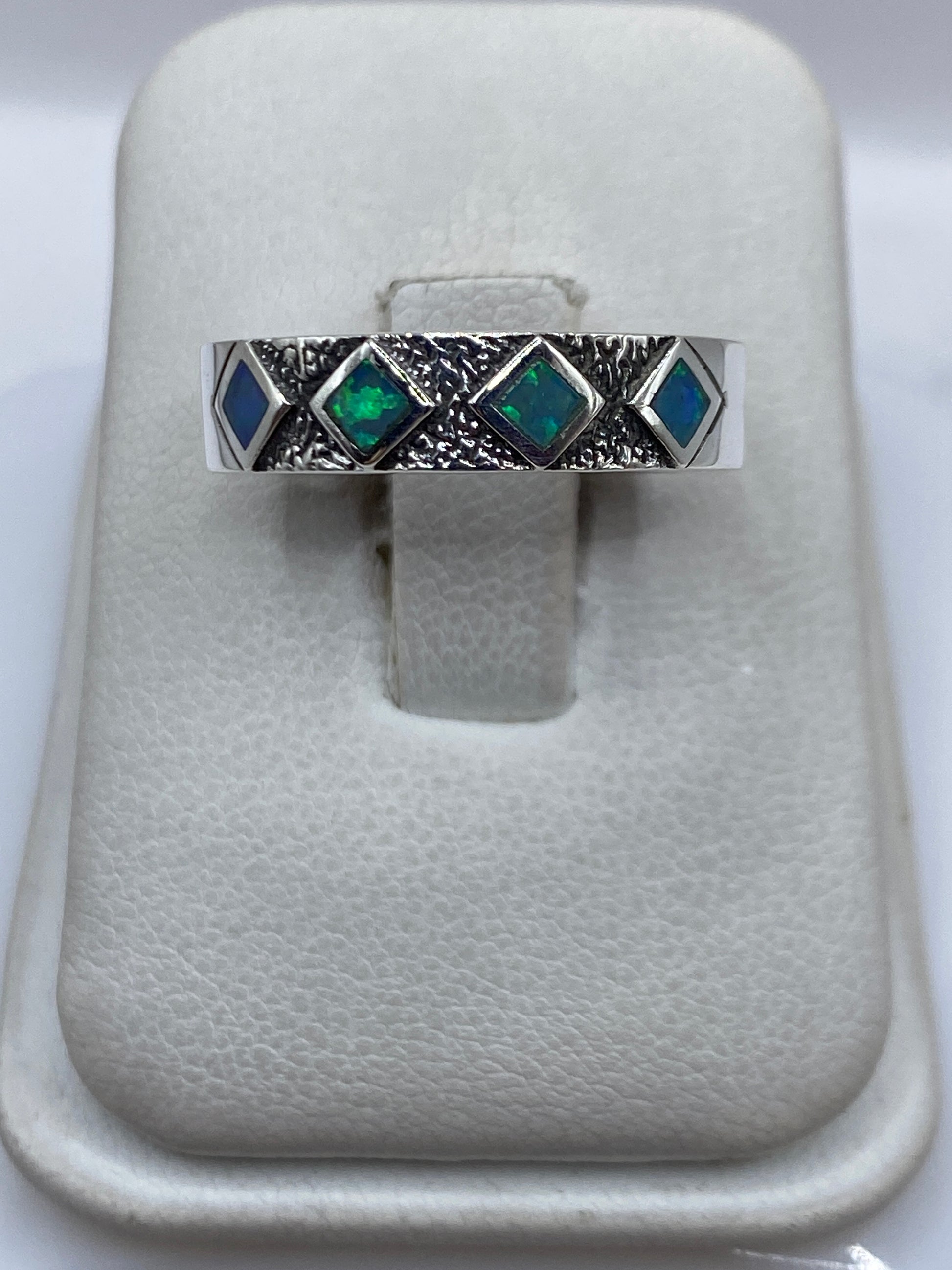 Anillo de plata .950 con ópalo de fuego azul cielo, vista frontal sobre presentador blanco