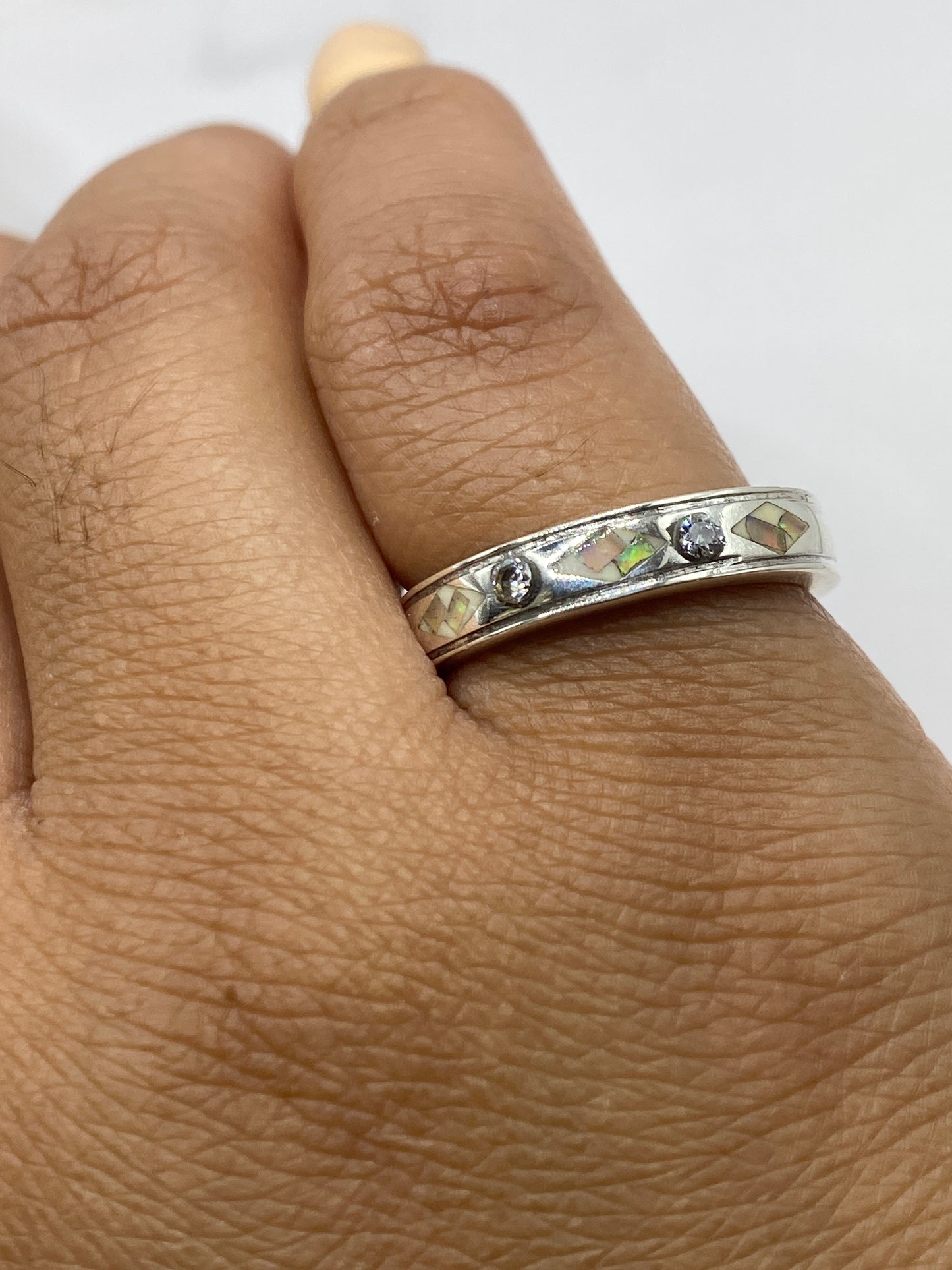 Anillo puesto en dedo mostrando el Quinto .950 y brillo iridiscente del ópalo