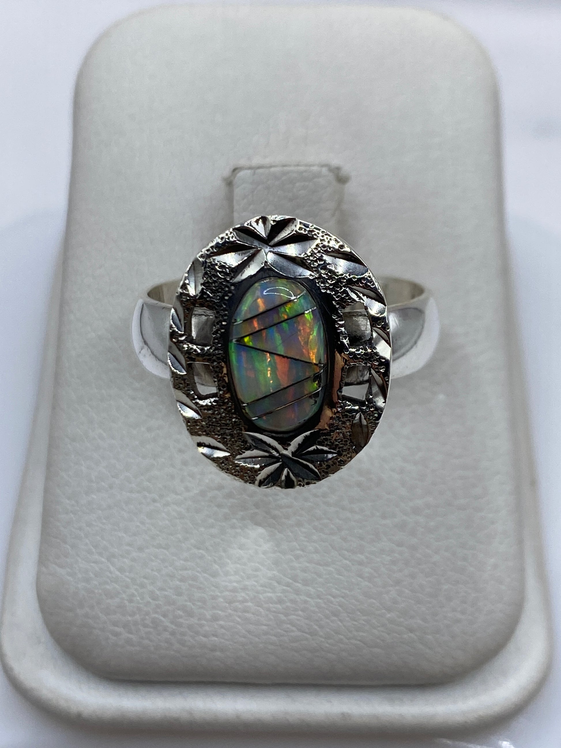 Anillo de plata .950 con ópalo de fuego en marco ornamental, mostrando el juego de colores natural de la piedra