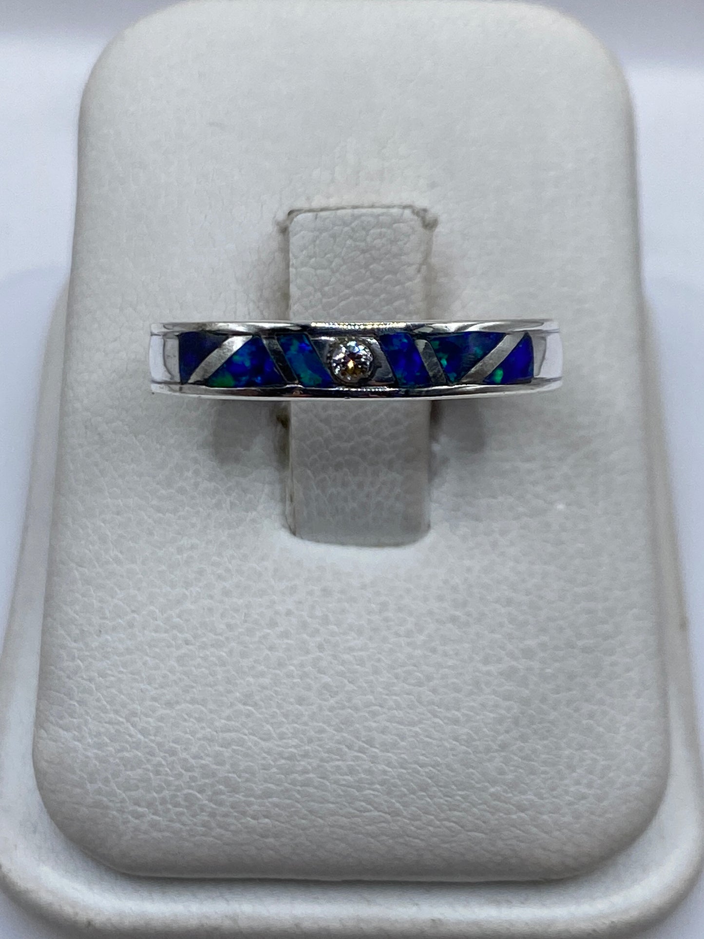 Anillo de plata .950 con ópalo de fuego azul sobre joyero blanco, vista superior