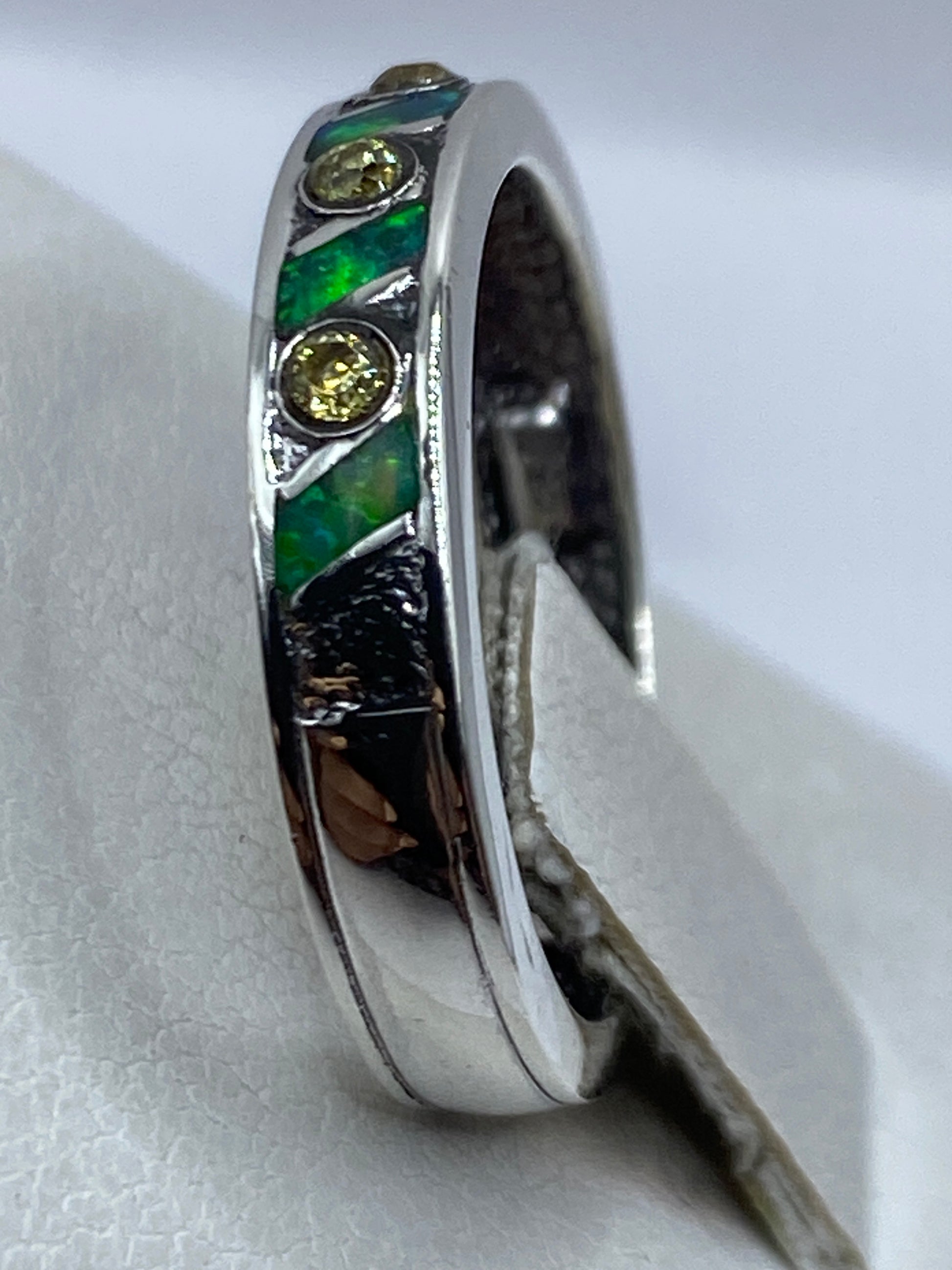 Detalle lateral del anillo en dedo, revelando el brillo del ópalo de fuego