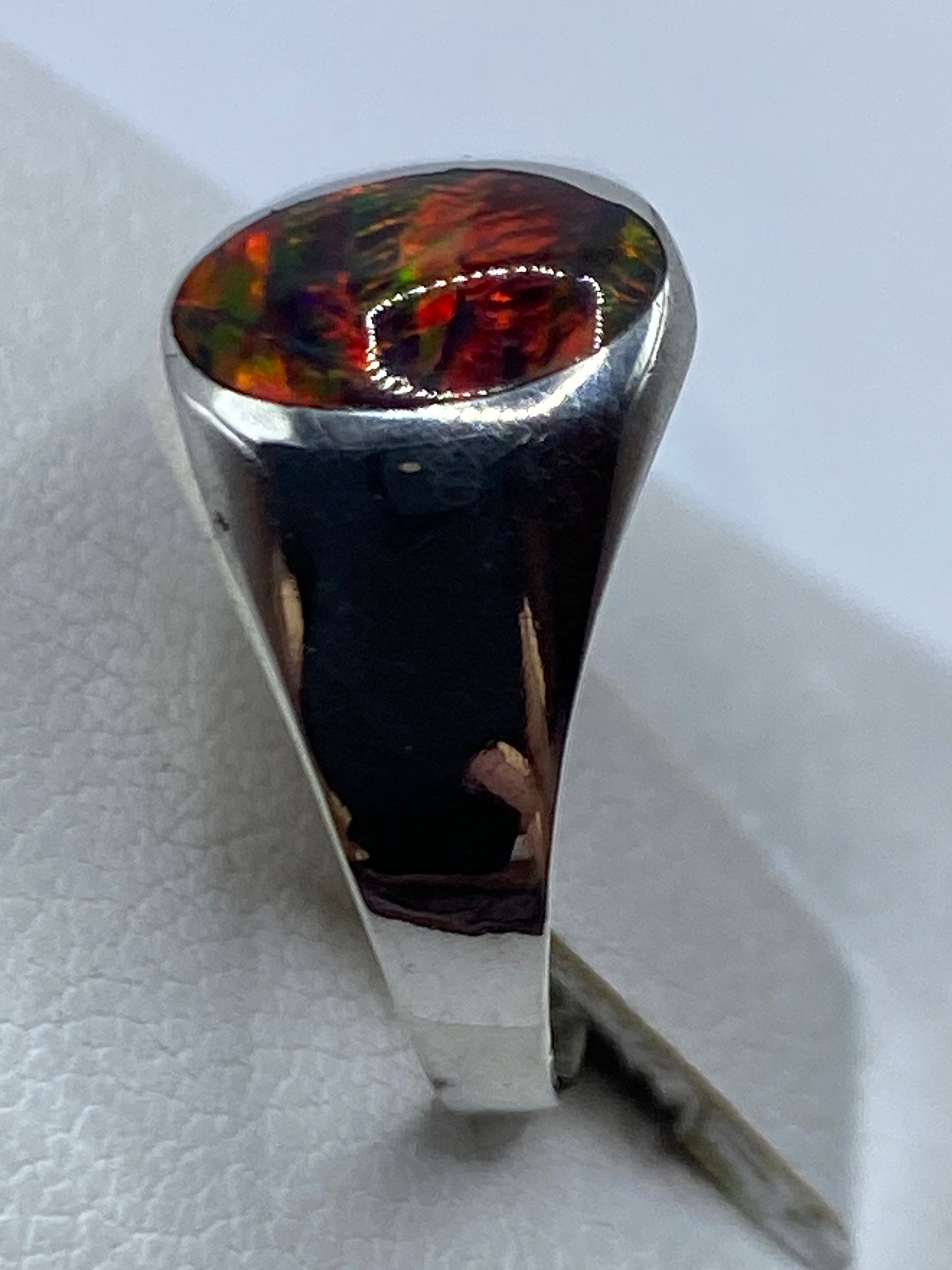 Detalle del ópalo de fuego con reflejos rojos, verdes y azules en la mano