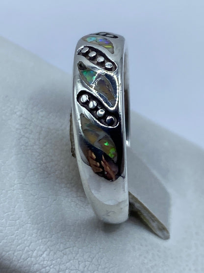 Anillo llevado en el dedo mostrando el ópalo brillante con tonos verdes, azules y naranjas