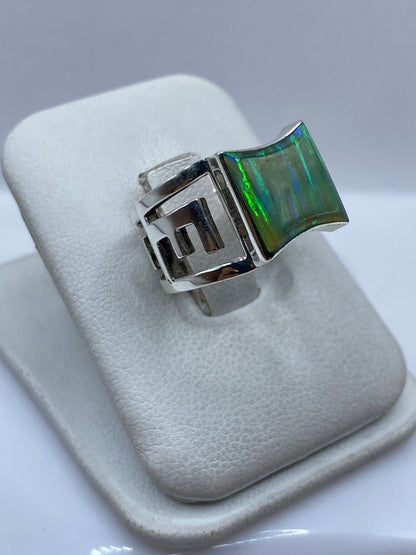 Vista frontal del anillo de ópalo de fuego con efecto iridiscente en verde y azul