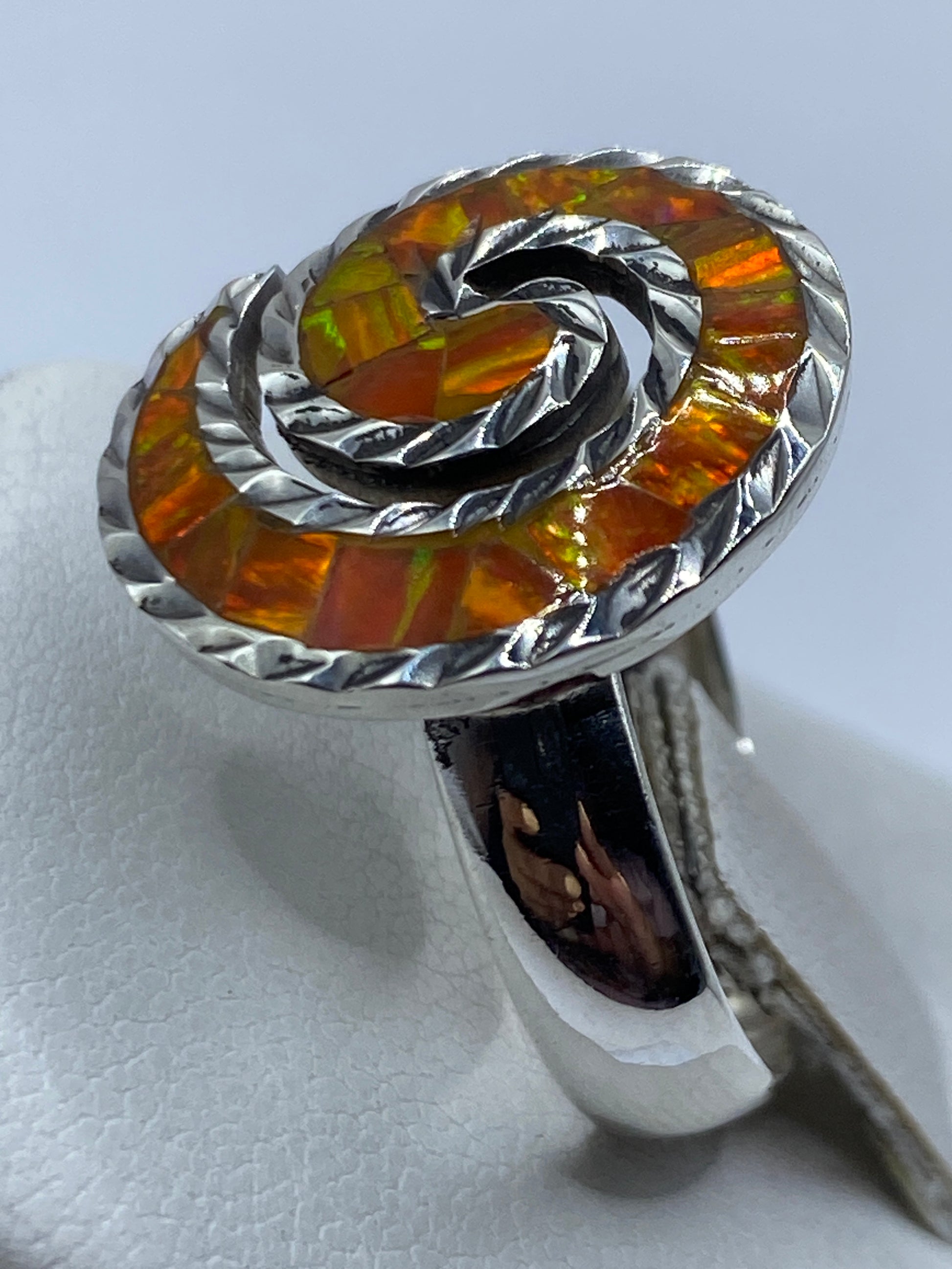 Anillo ópalo de fuego naranja en dedo — luz reflejada en la piedra