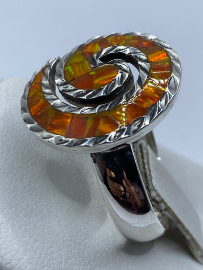 Anillo ópalo de fuego naranja en dedo — luz reflejada en la piedra