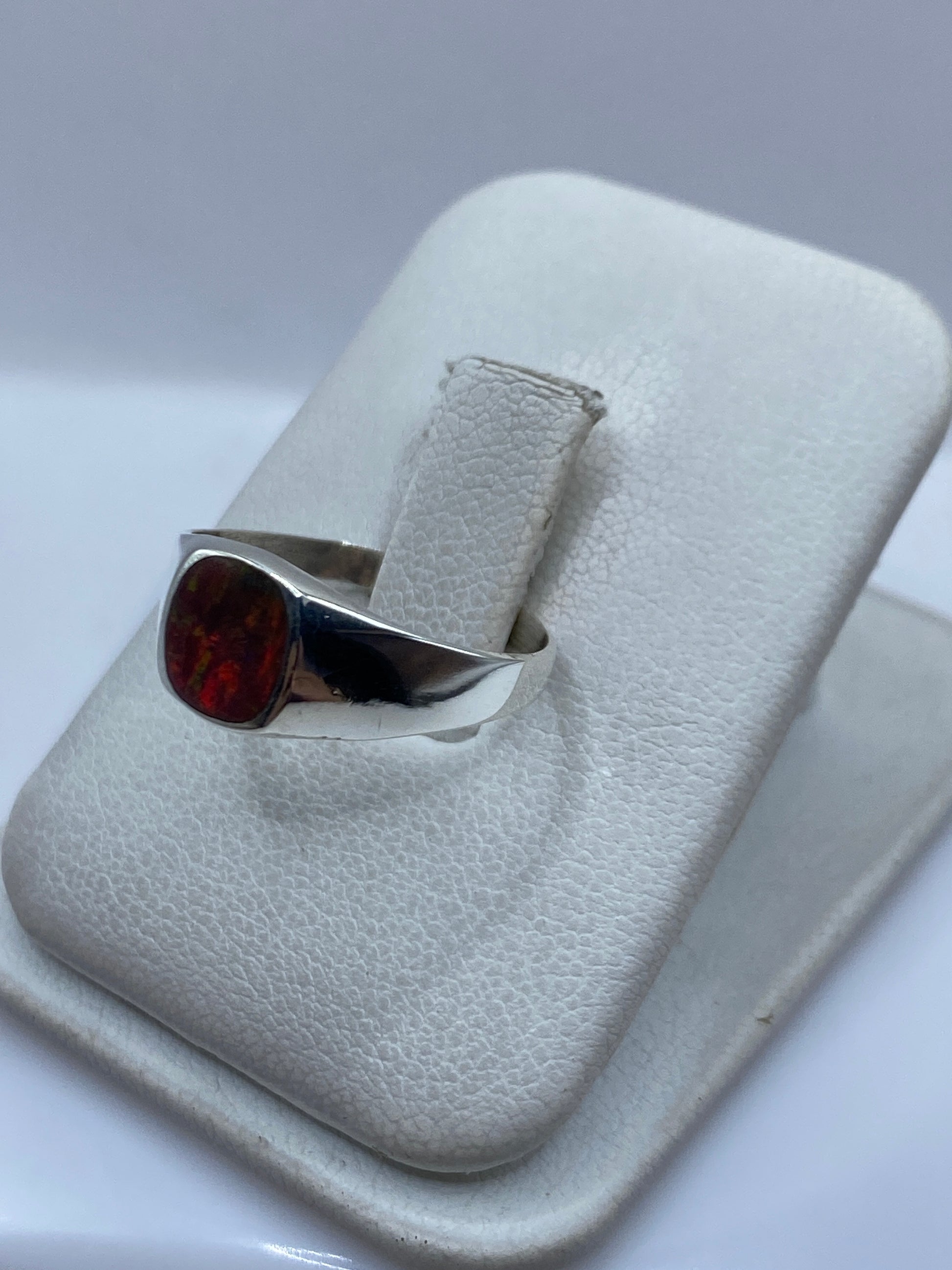 Vista frontal del anillo mostrando el ópalo de fuego con tonos rojos, naranjas y dorados