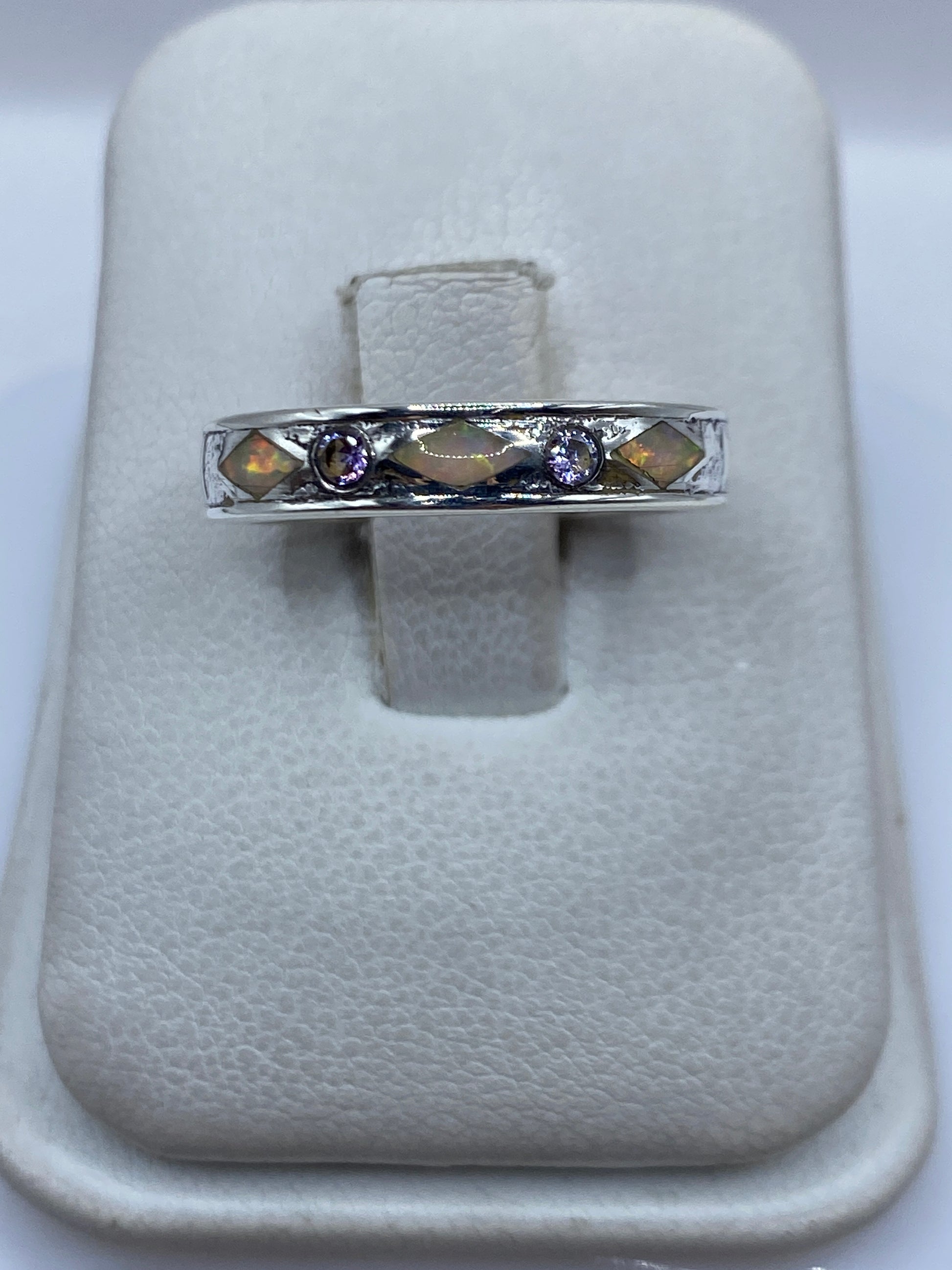 Anillo de plata .950 con ópalo de fuego multicolor en tonos naranja, rojo y verde, sobre almohada blanca
