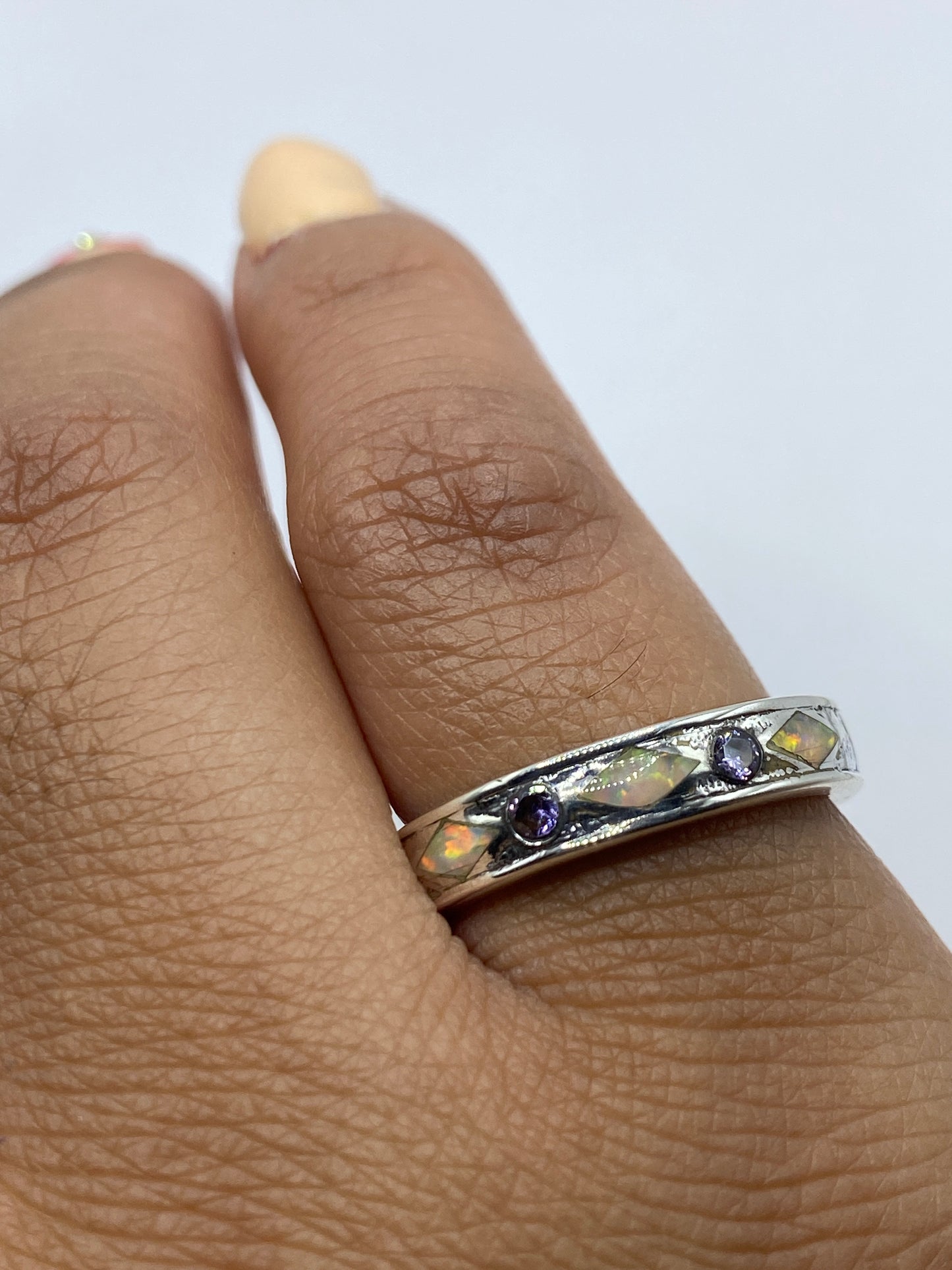 Anillo en el dedo mostrando los tonos vivos del ópalo sobre la piel