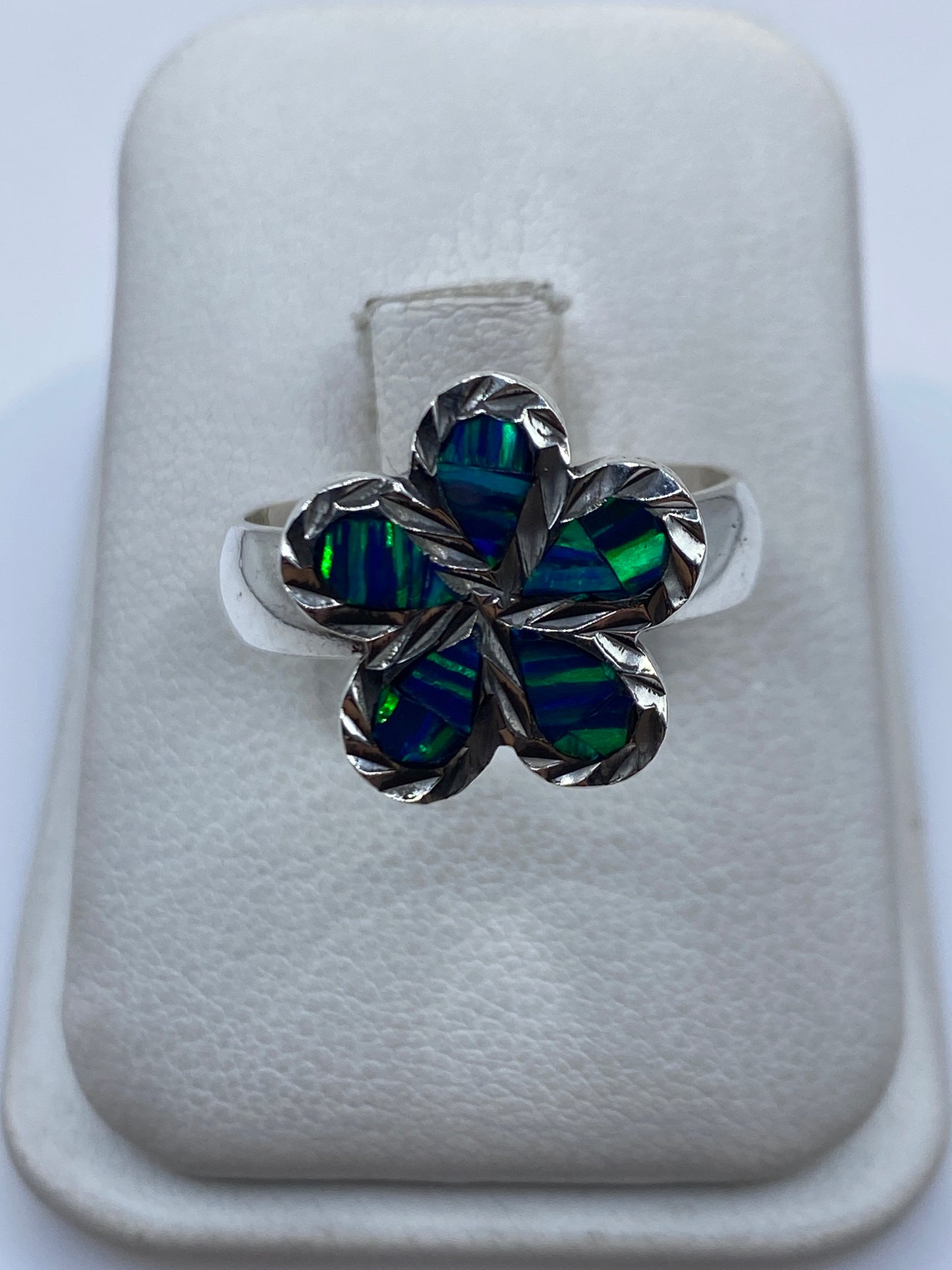 Anillo floral de plata .950 con ópal de fuego azul en la mano de una mujer
